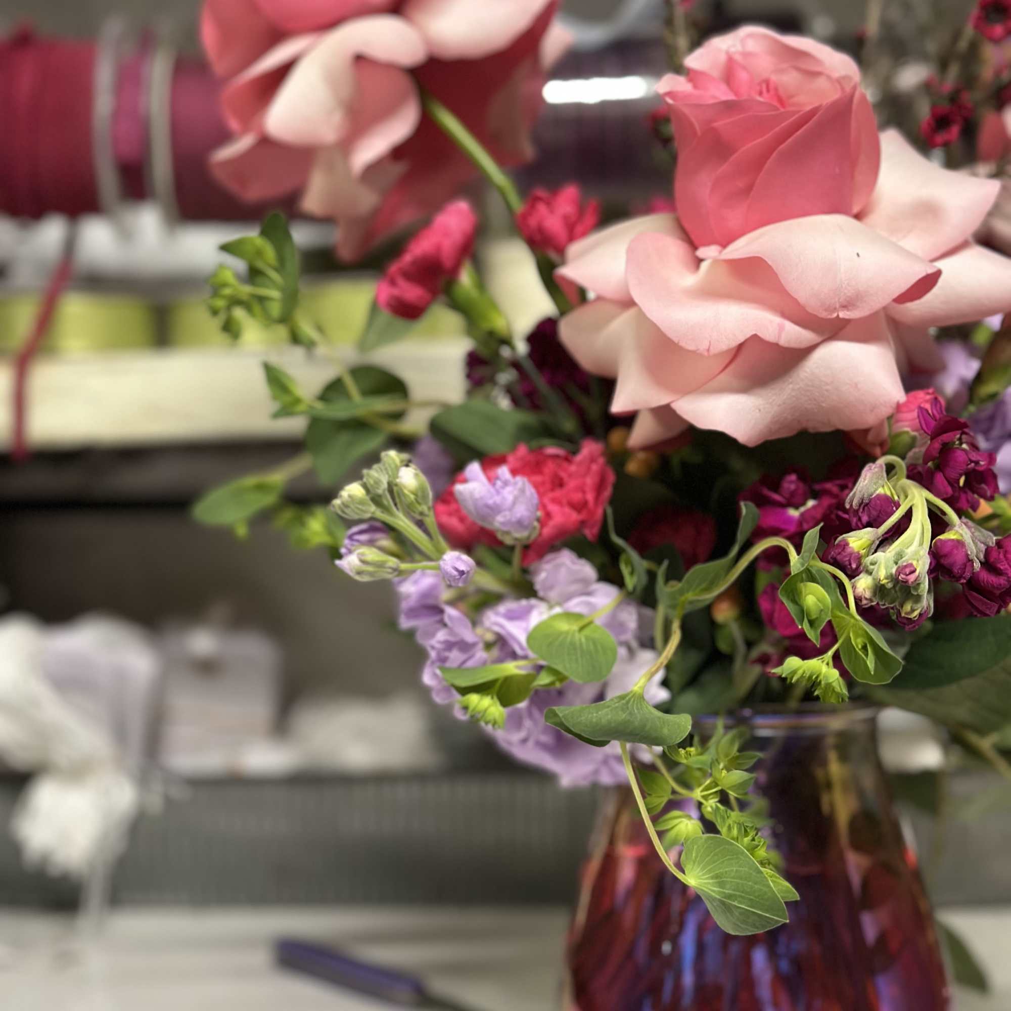 Pink roses and purple flowers arranged in a glass vase