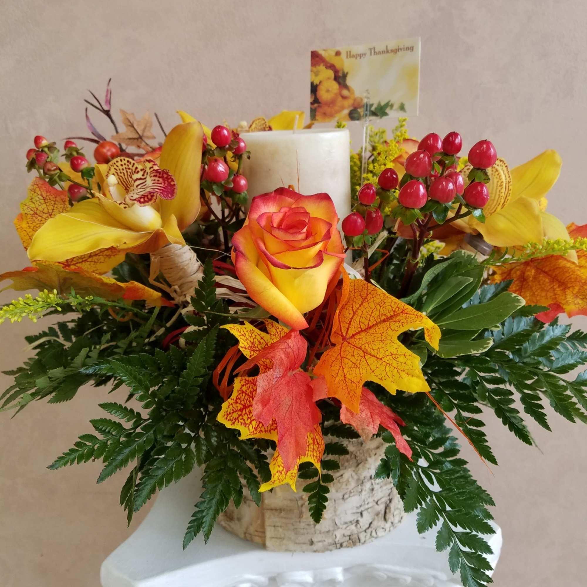 Autumn floral arrangement with a candle and Thanksgiving card in a basket