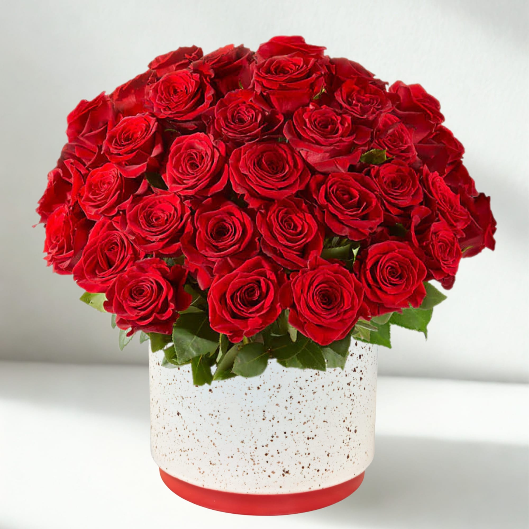 Red roses arranged in a white speckled pot