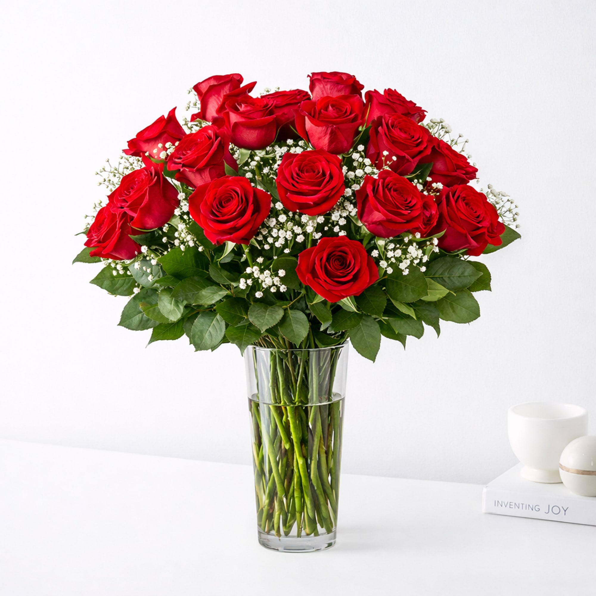 Red roses arranged in a clear glass vase with baby's breath