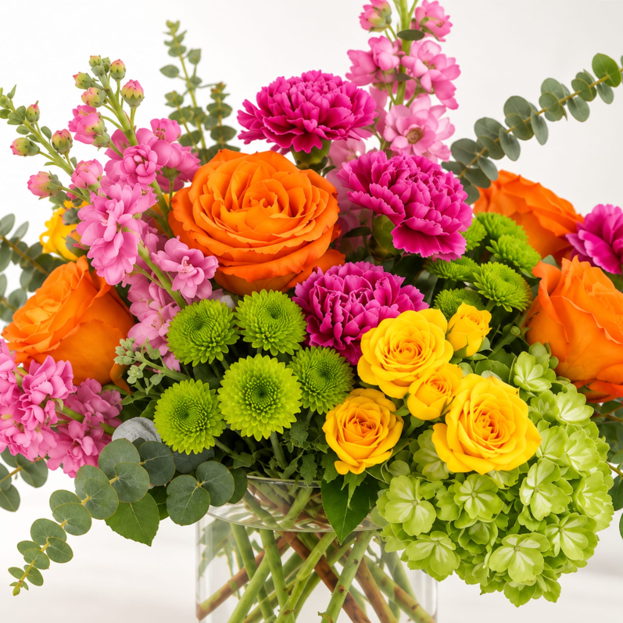 Bright mixed bouquet in a glass vase with orange, pink, yellow, and green blooms