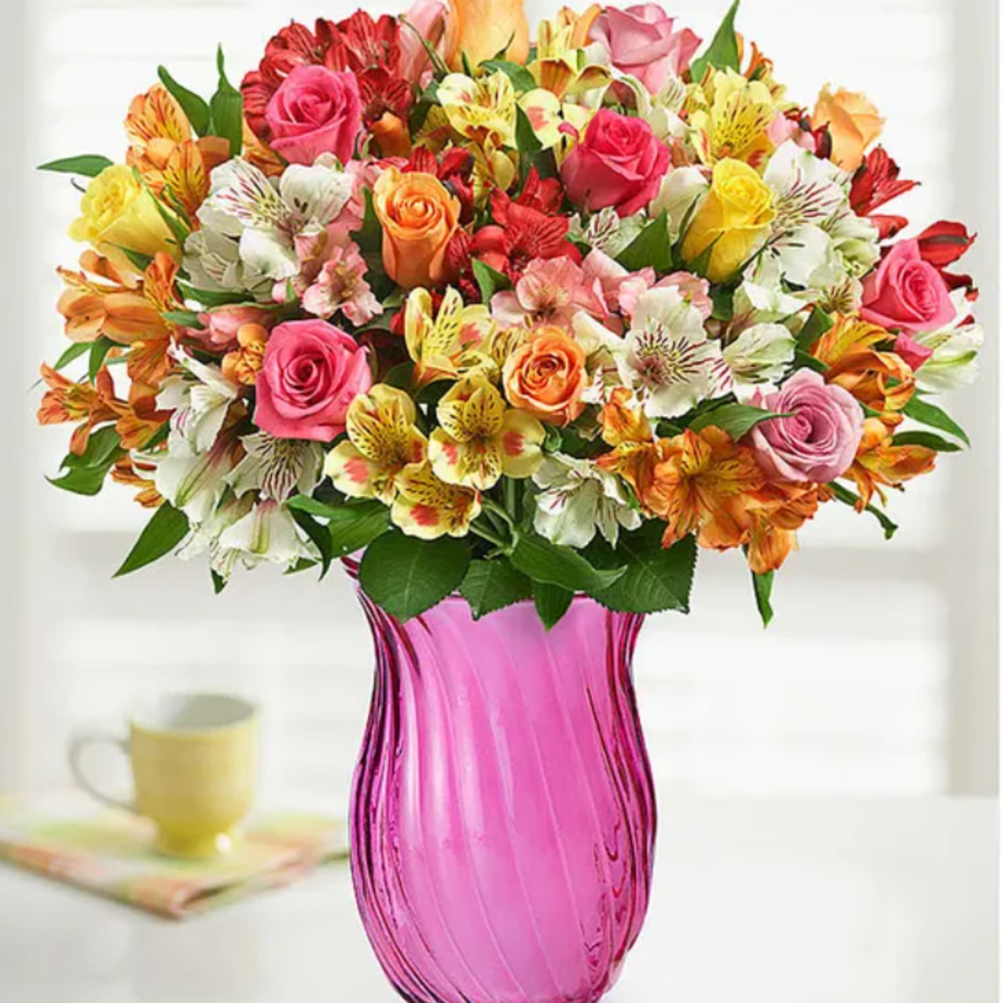 A mix of available colored roses and alstroemeria. Vase color will be