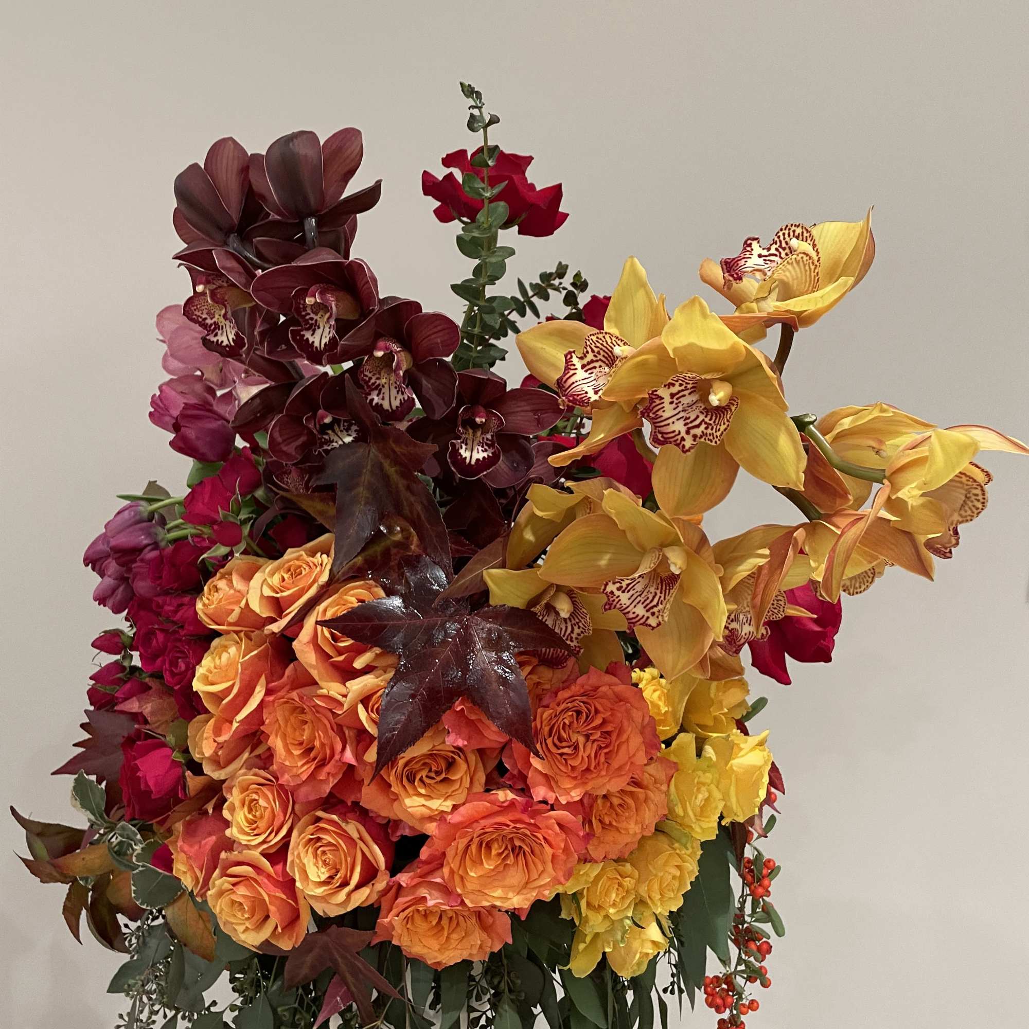 Large bouquet of orange roses and yellow orchids with dark burgundy flowers