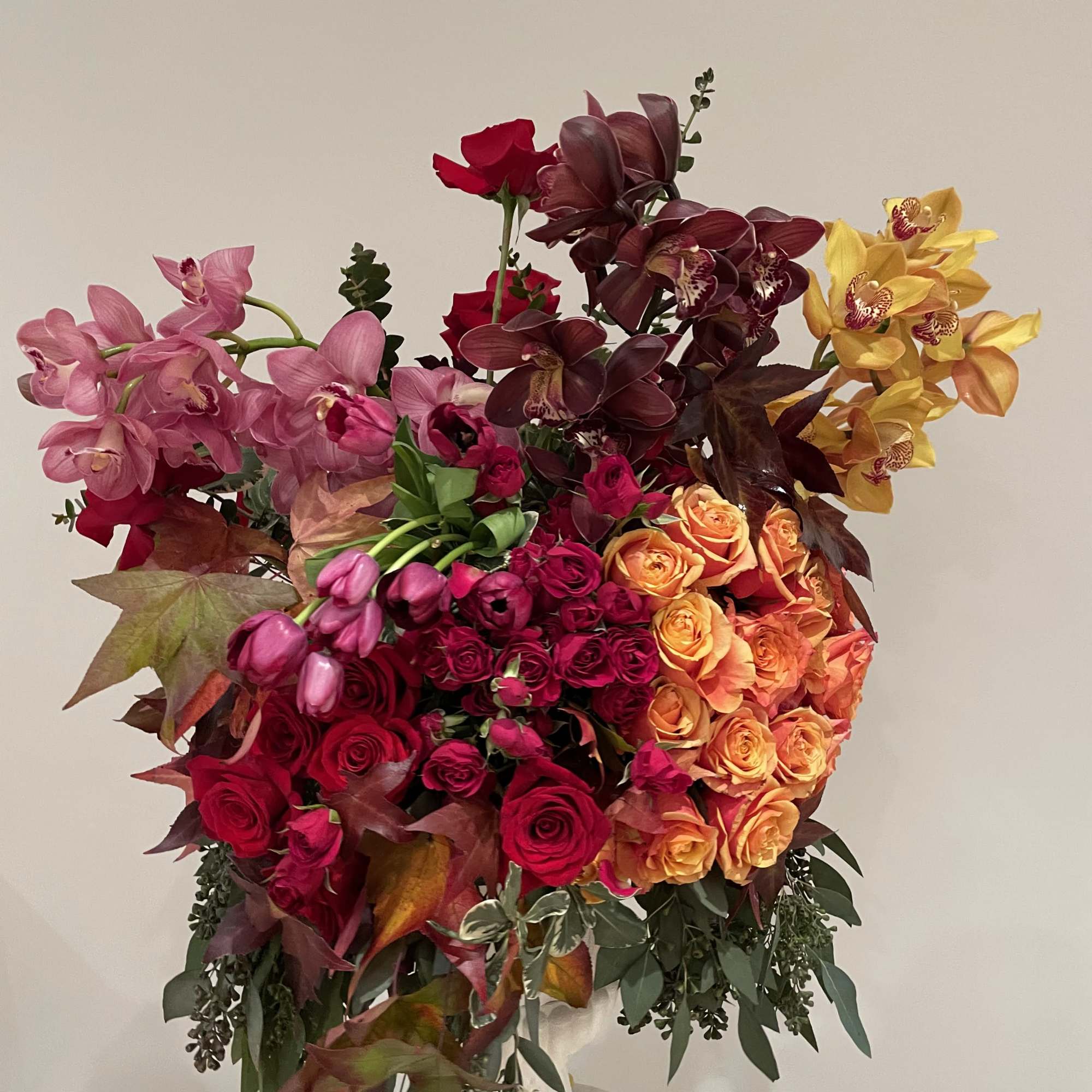 Large bouquet of roses and orchids in pink, red, orange, and yellow