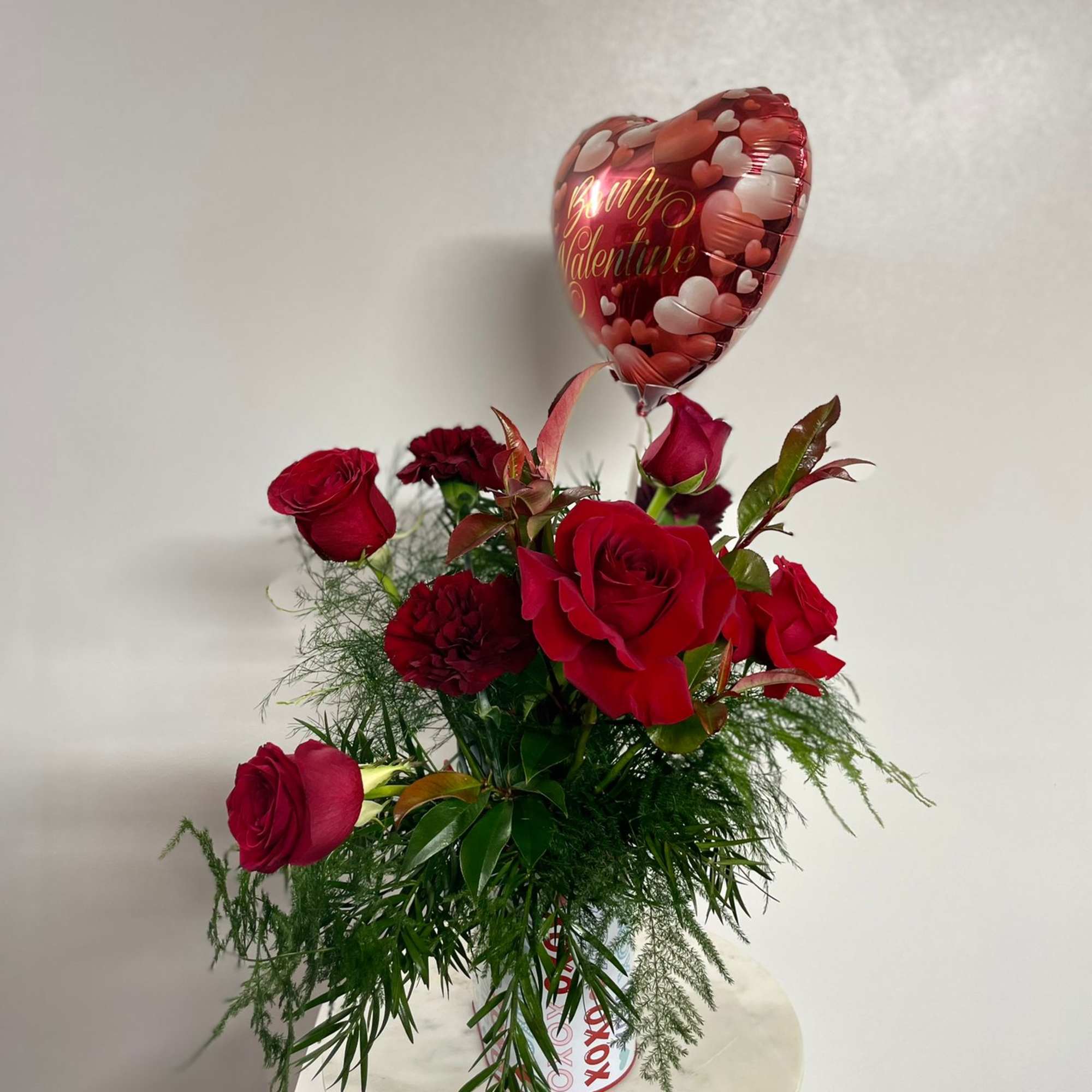 Red roses in a vase with a heart-shaped Valentine balloon