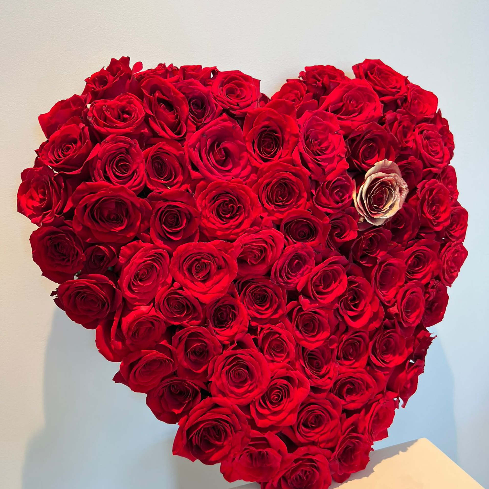 Heart-shaped arrangement of red roses on a white pedestal