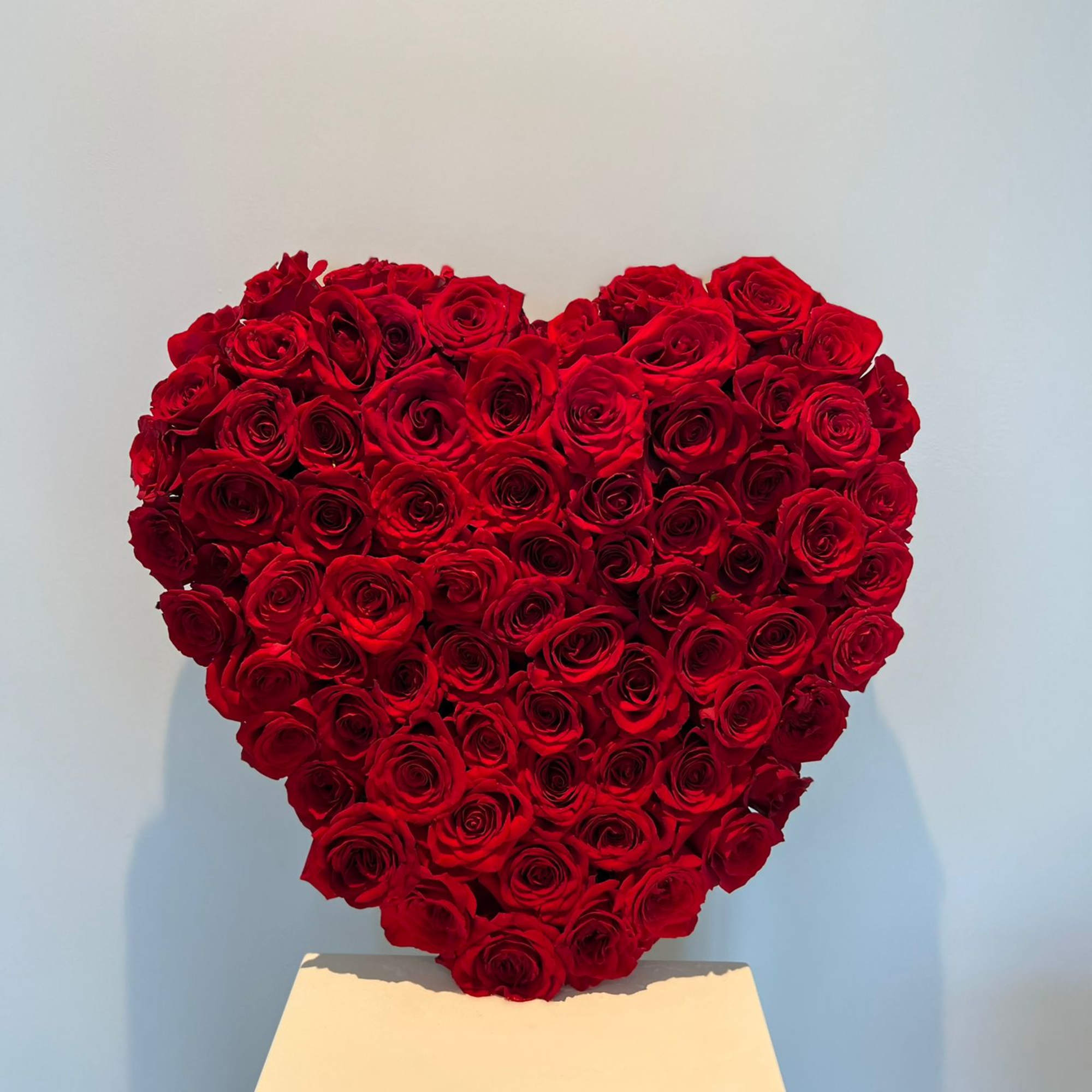 Heart-shaped arrangement of red roses on a pedestal