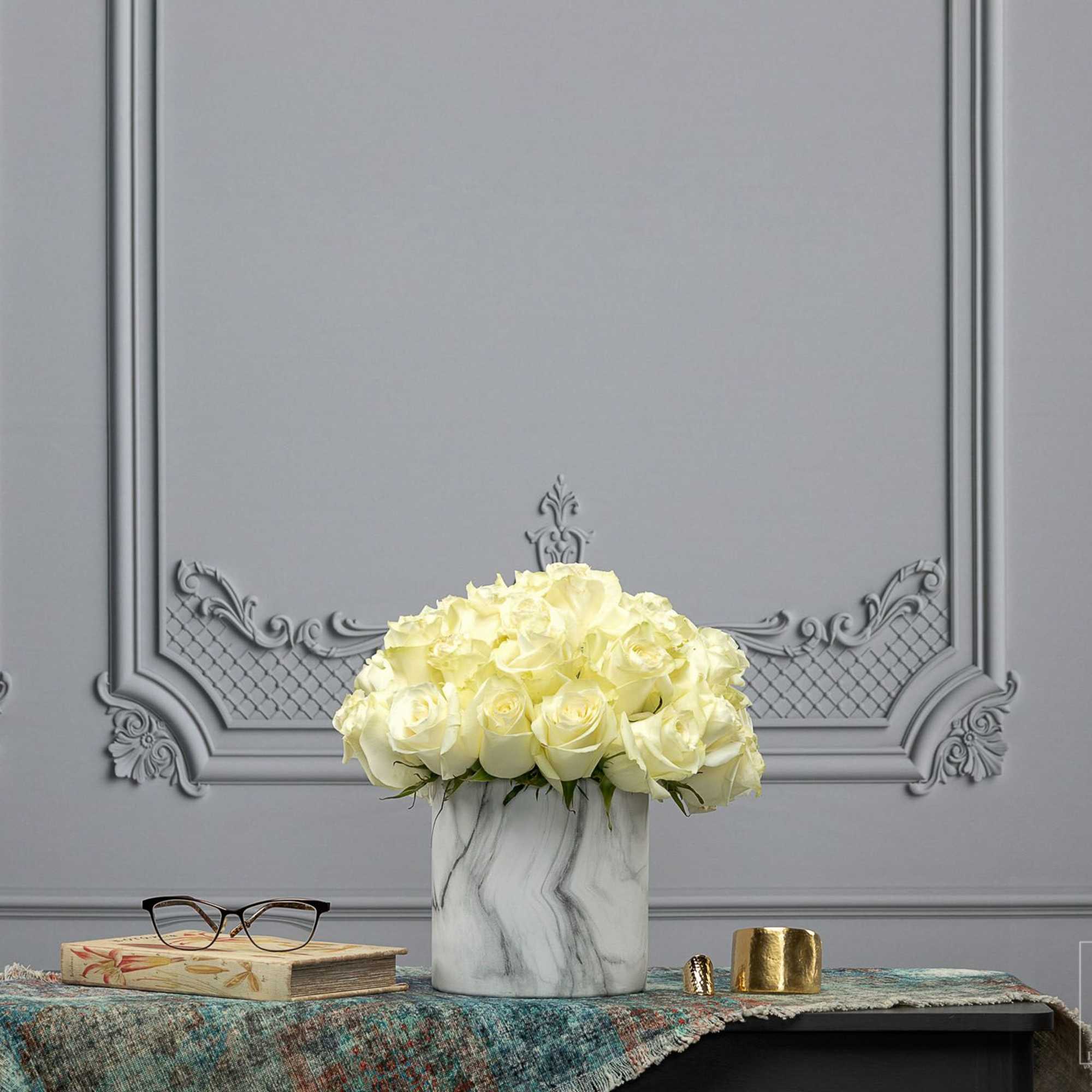 White rose arrangement in a marble-pattern vase on a table