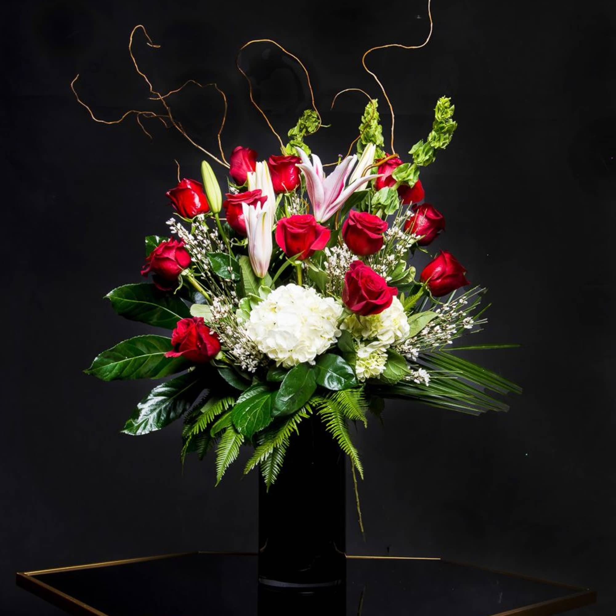 Red roses and white lilies arranged in a tall black vase