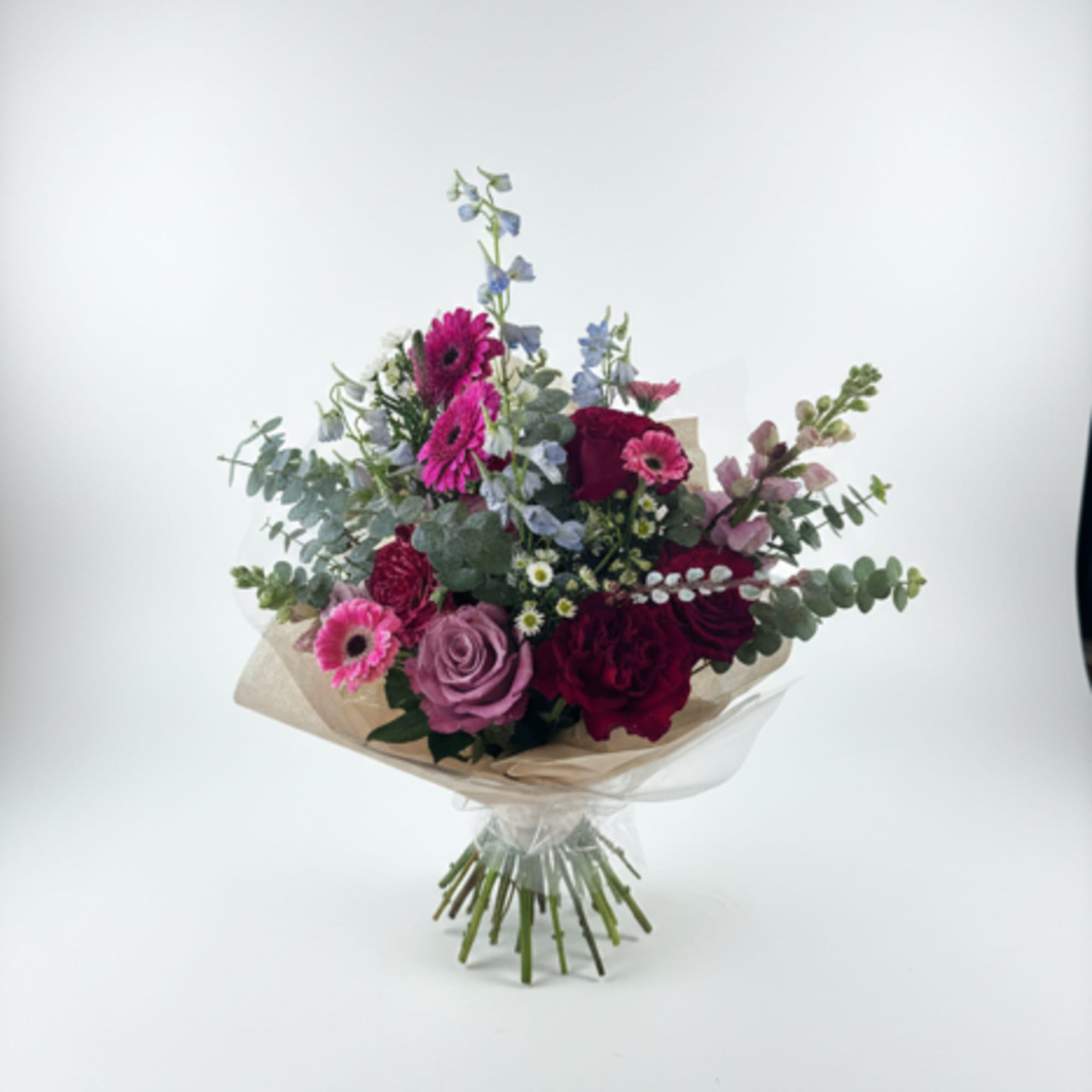 Bouquet of pink, purple, and blue flowers wrapped in beige paper