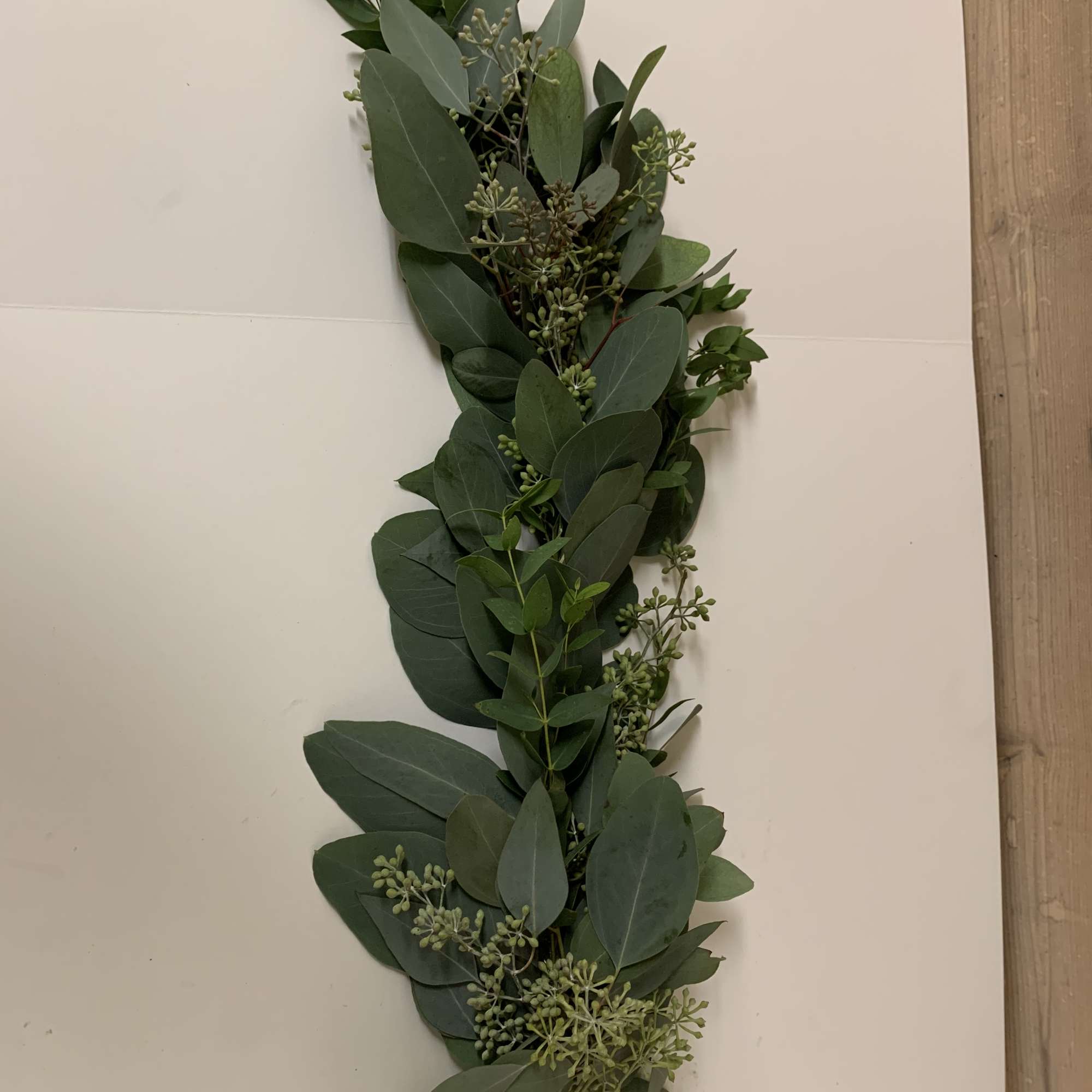 A long eucalyptus greenery garland laid on a white surface