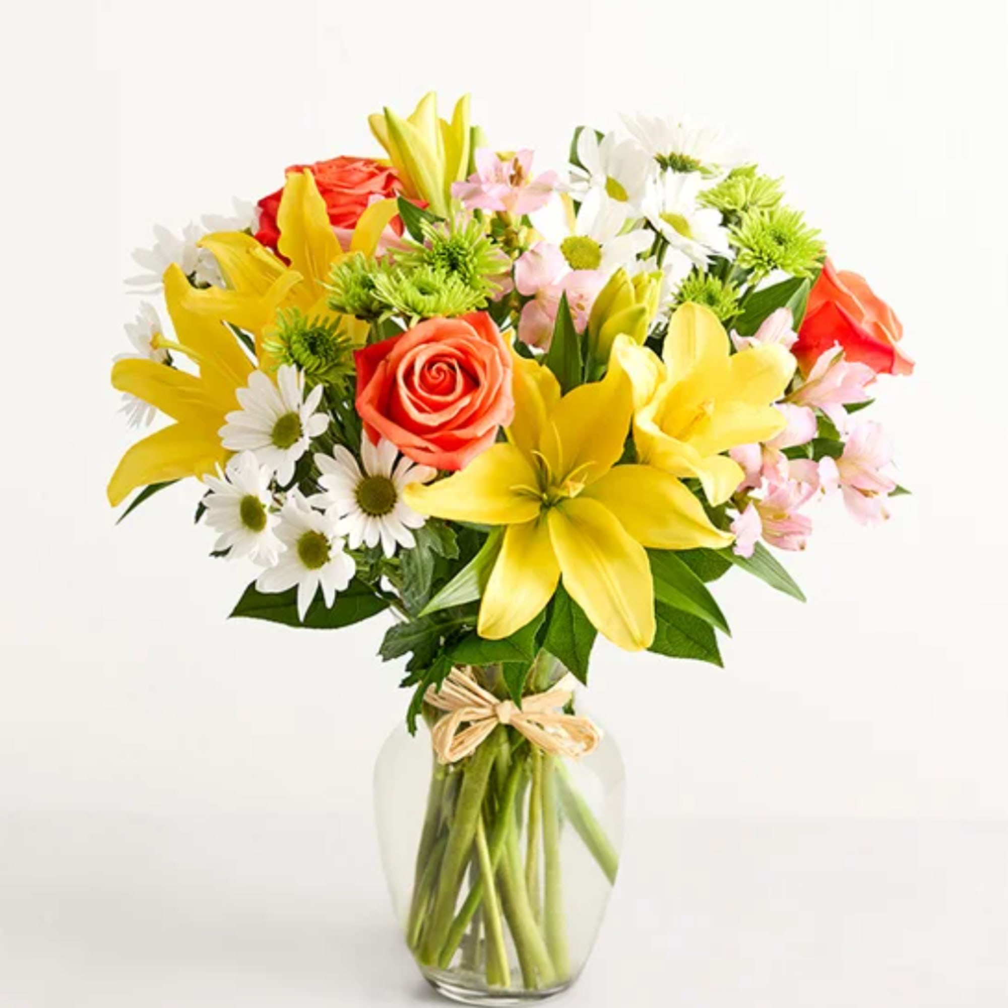 Mixed bouquet of yellow lilies, roses, and daisies in a glass vase