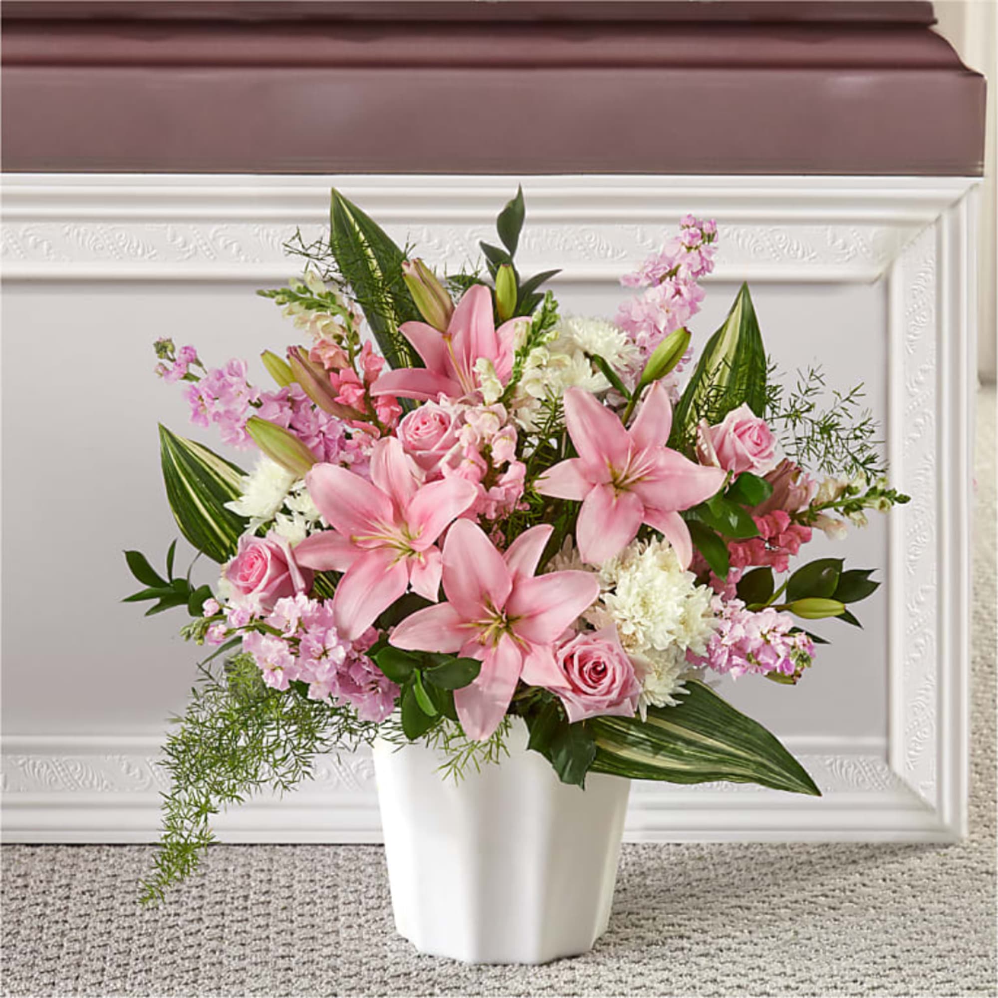 Pink lilies and roses arranged in a white vase
