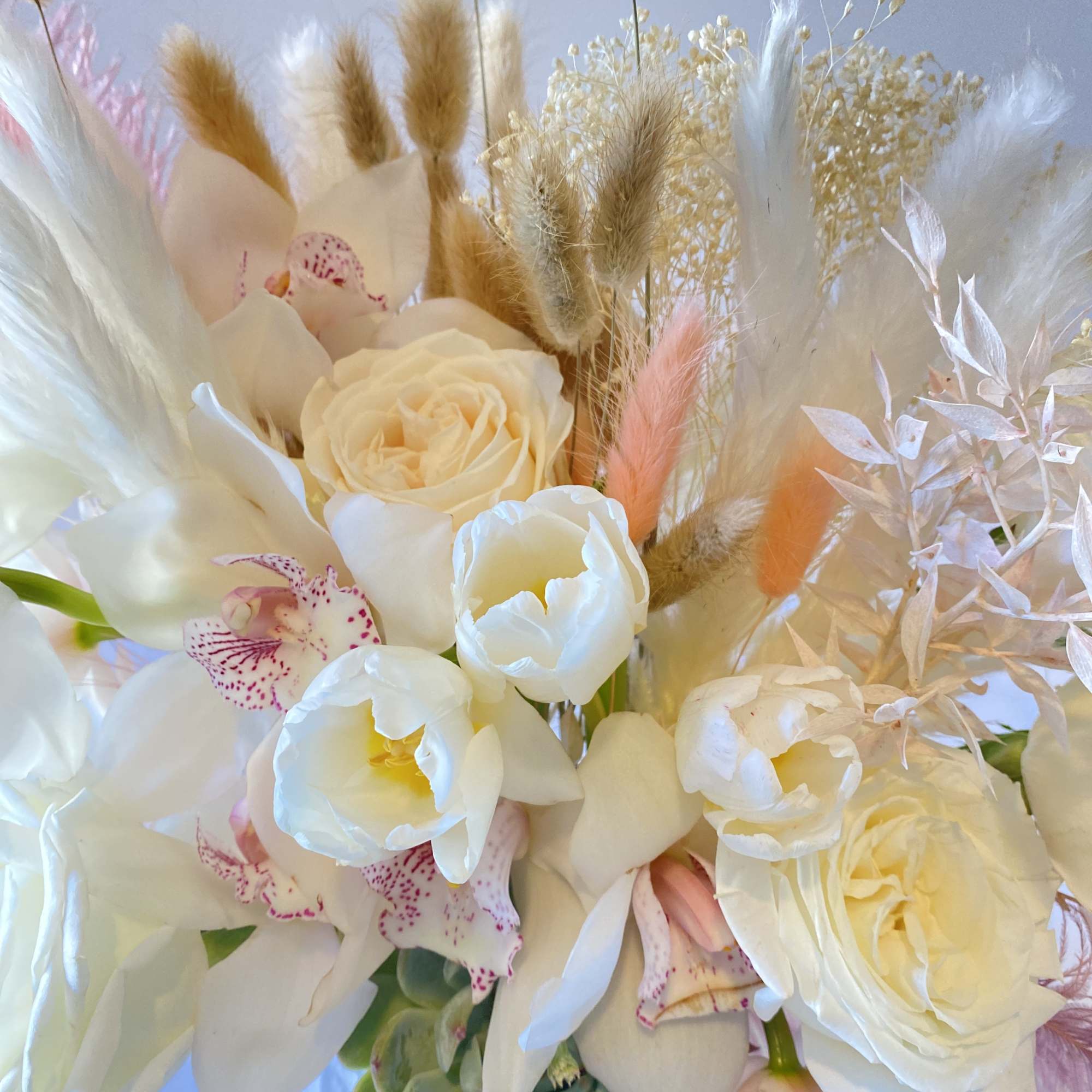 Bouquet of white roses, orchids, and tulips with dried grasses