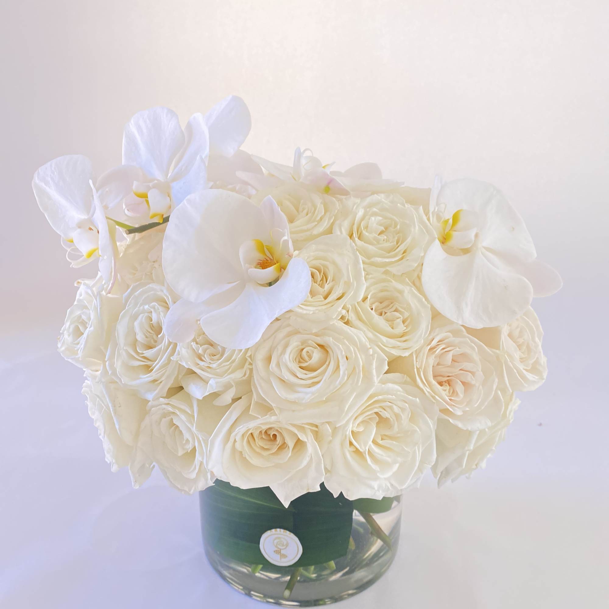 White rose bouquet with white orchids in a glass vase