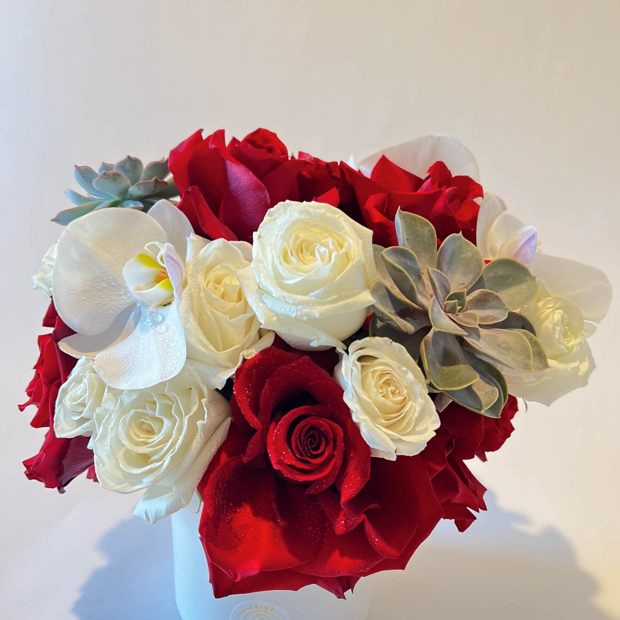 Bouquet of red and white roses with succulents in a white box
