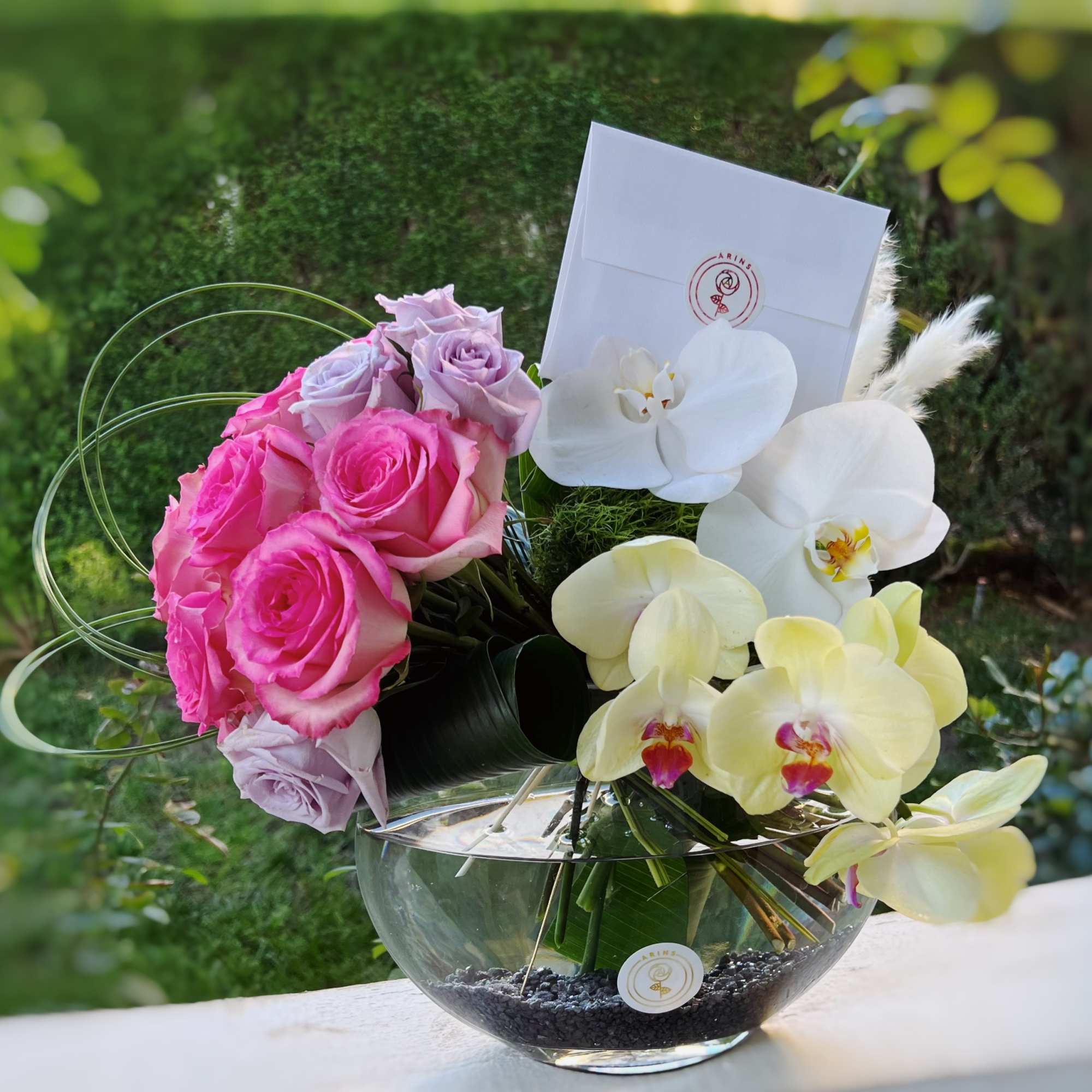 Pink roses and white orchids arranged in a glass bowl vase