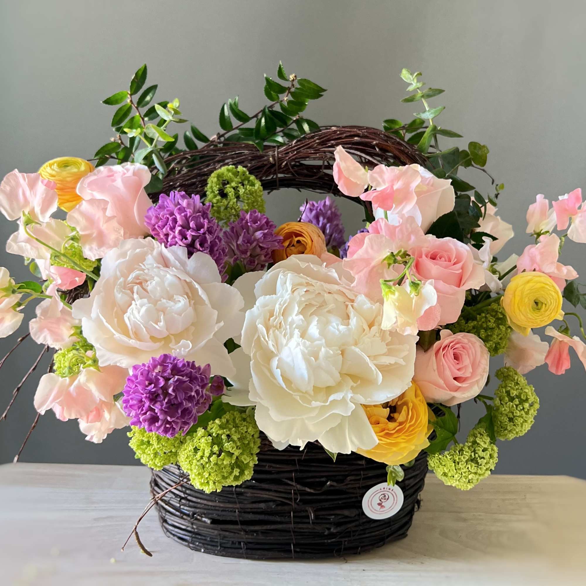 Basket arrangement of pink, white, yellow, and purple flowers