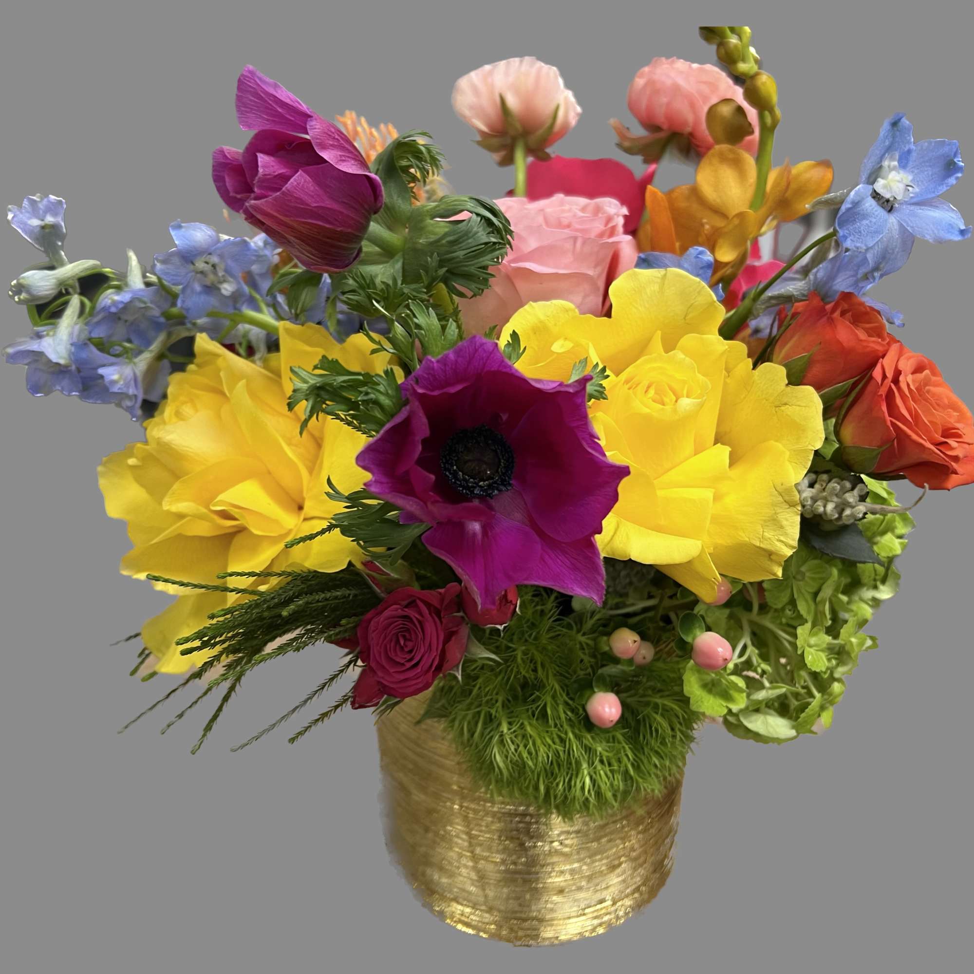 Colorful mixed bouquet in a gold vase with bright yellow, pink, purple, blue, and orange blooms