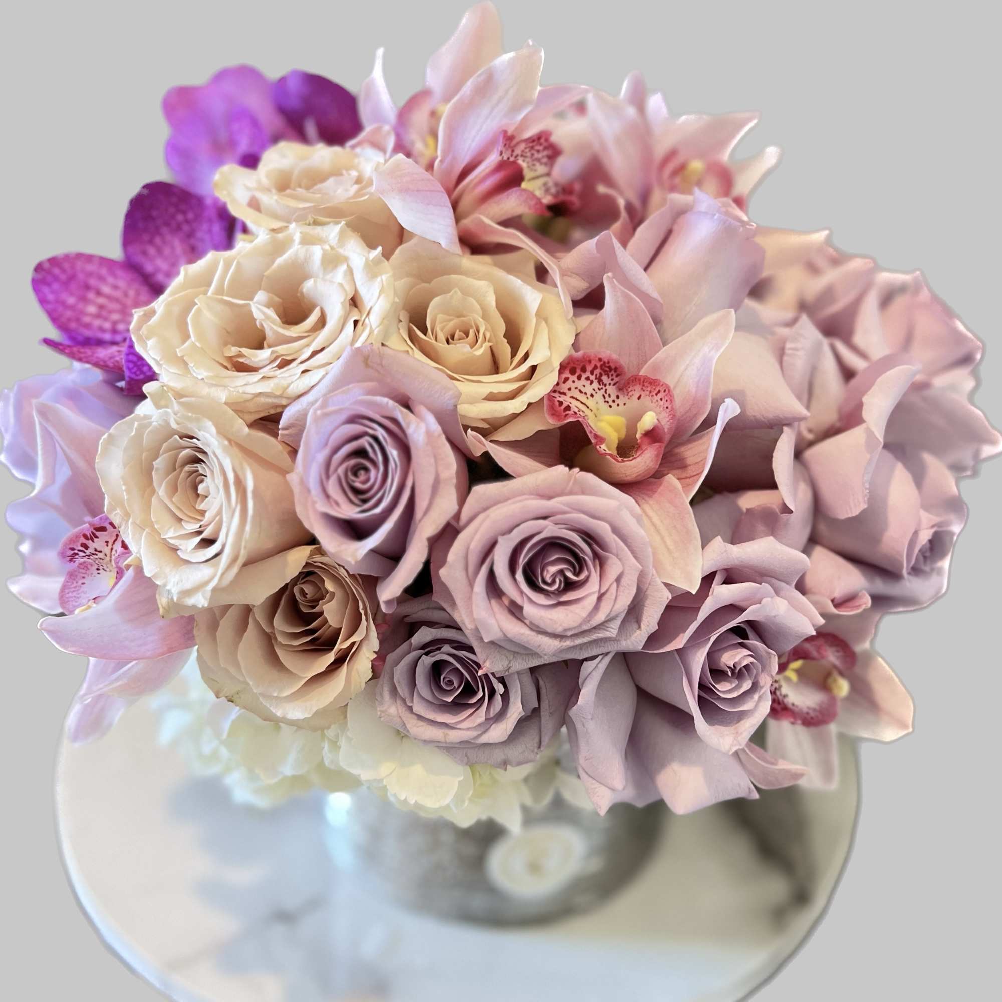 Bouquet of pastel roses and orchids in a clear vase
