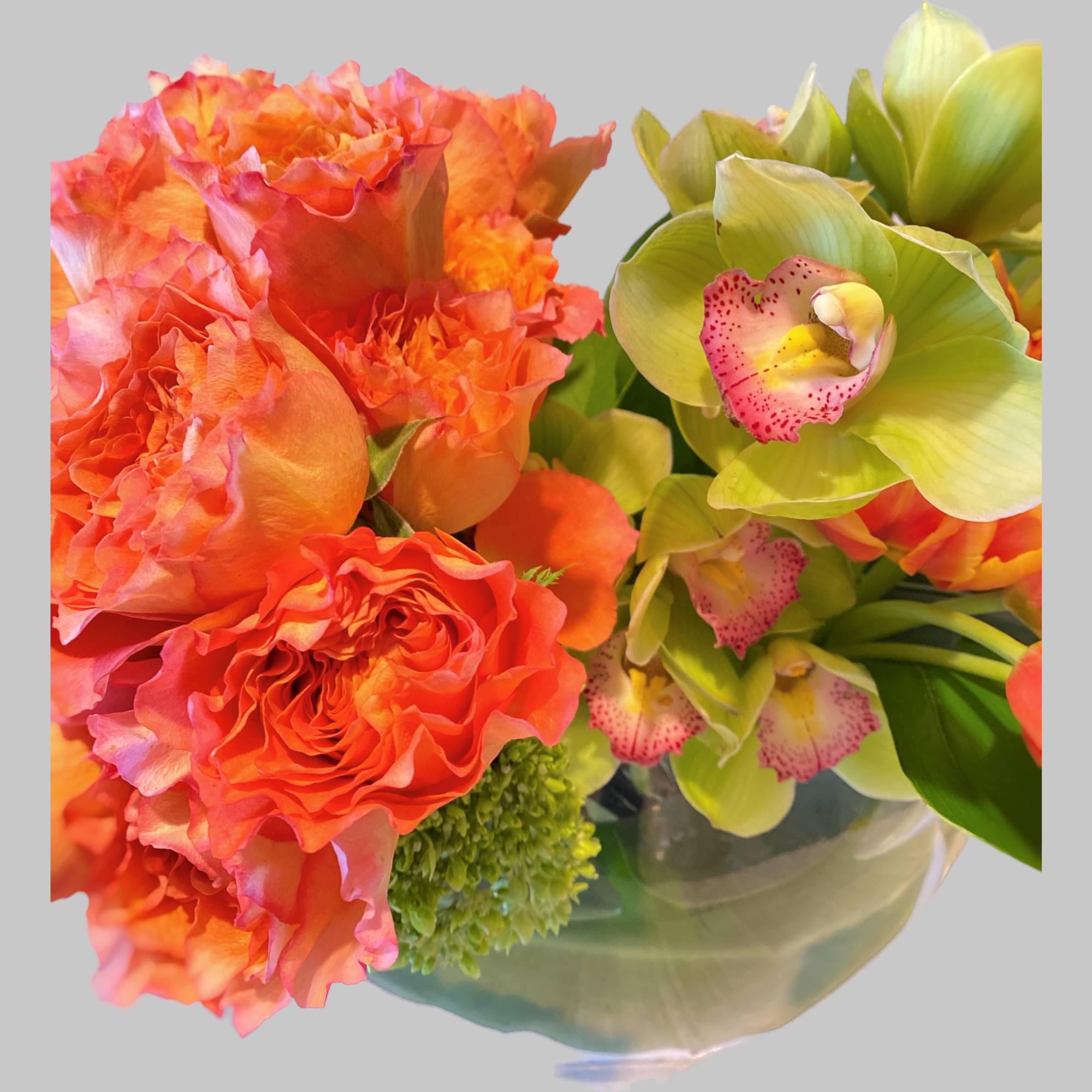 Orange roses and green orchids in a glass vase