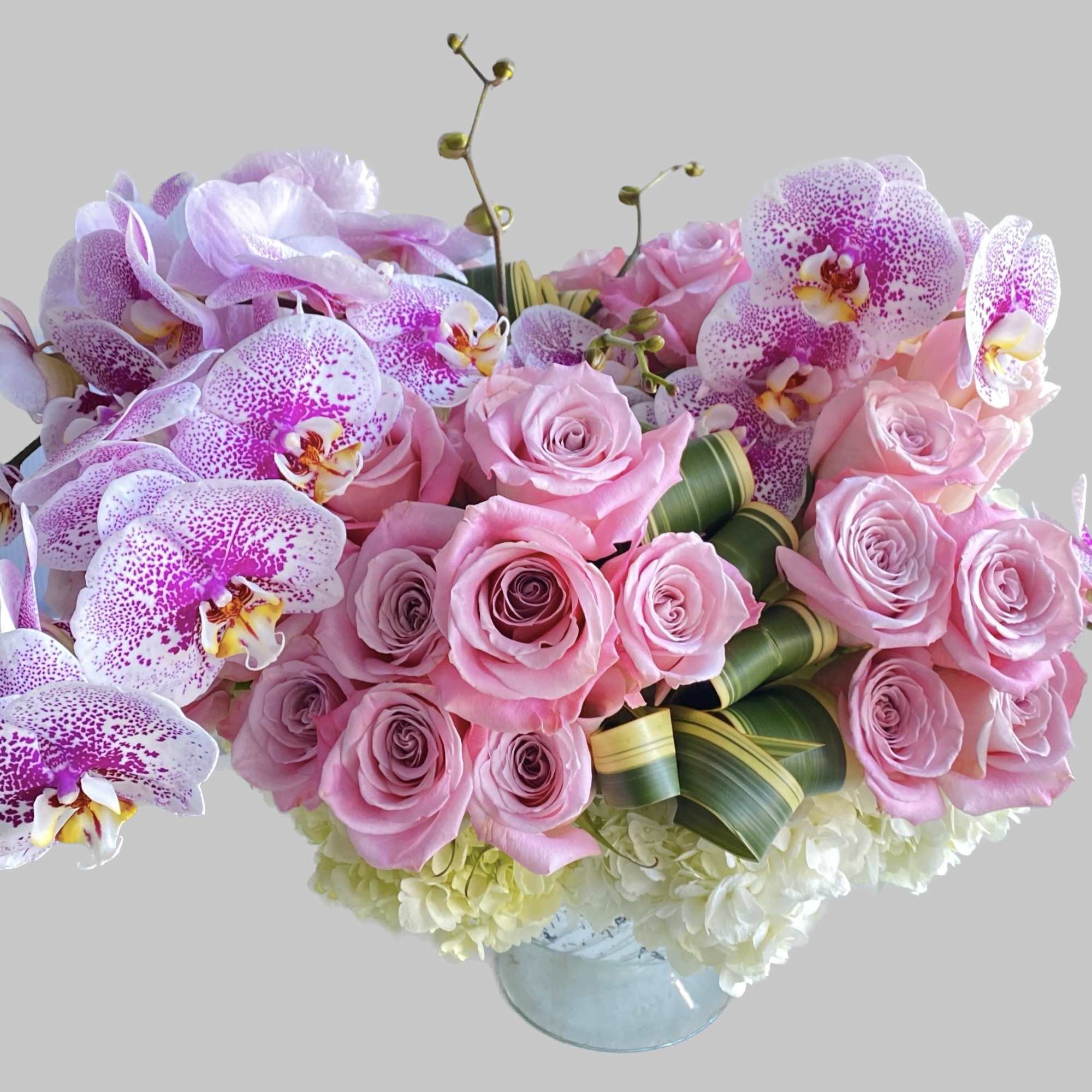 Pink roses and speckled orchids in a glass vase