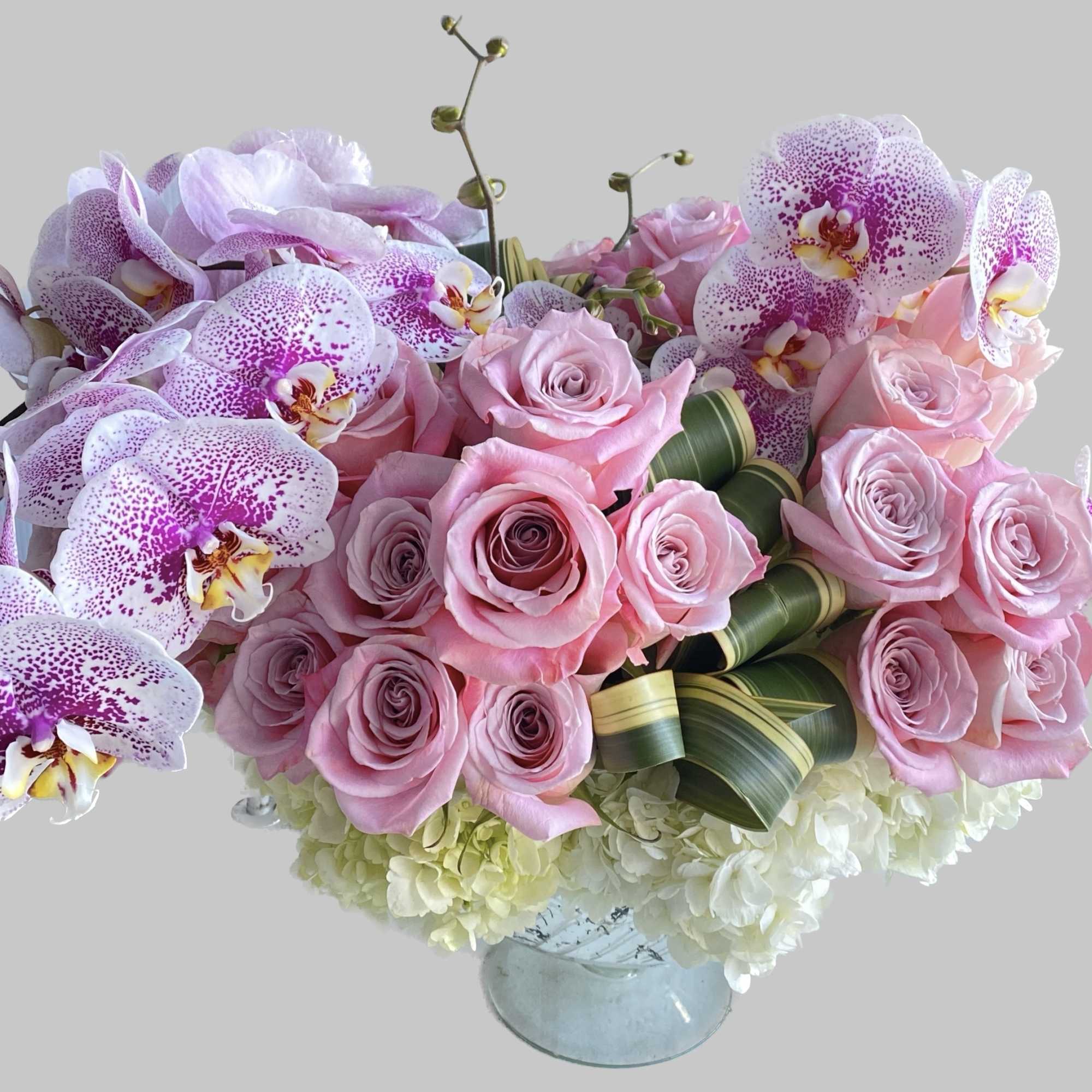 Pink roses and spotted orchids arranged in a glass vase