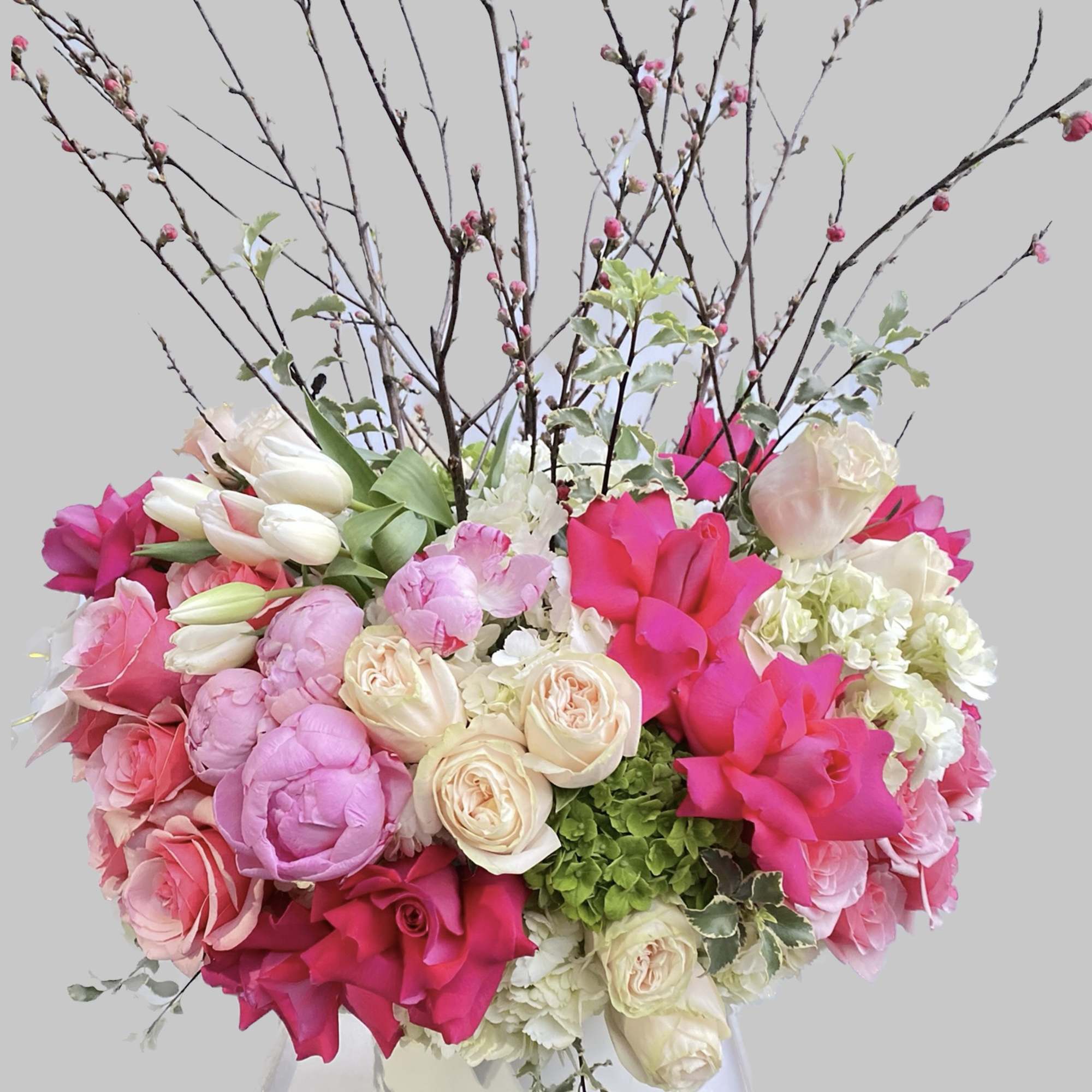 Pink and white floral arrangement in a white vase with tall branches