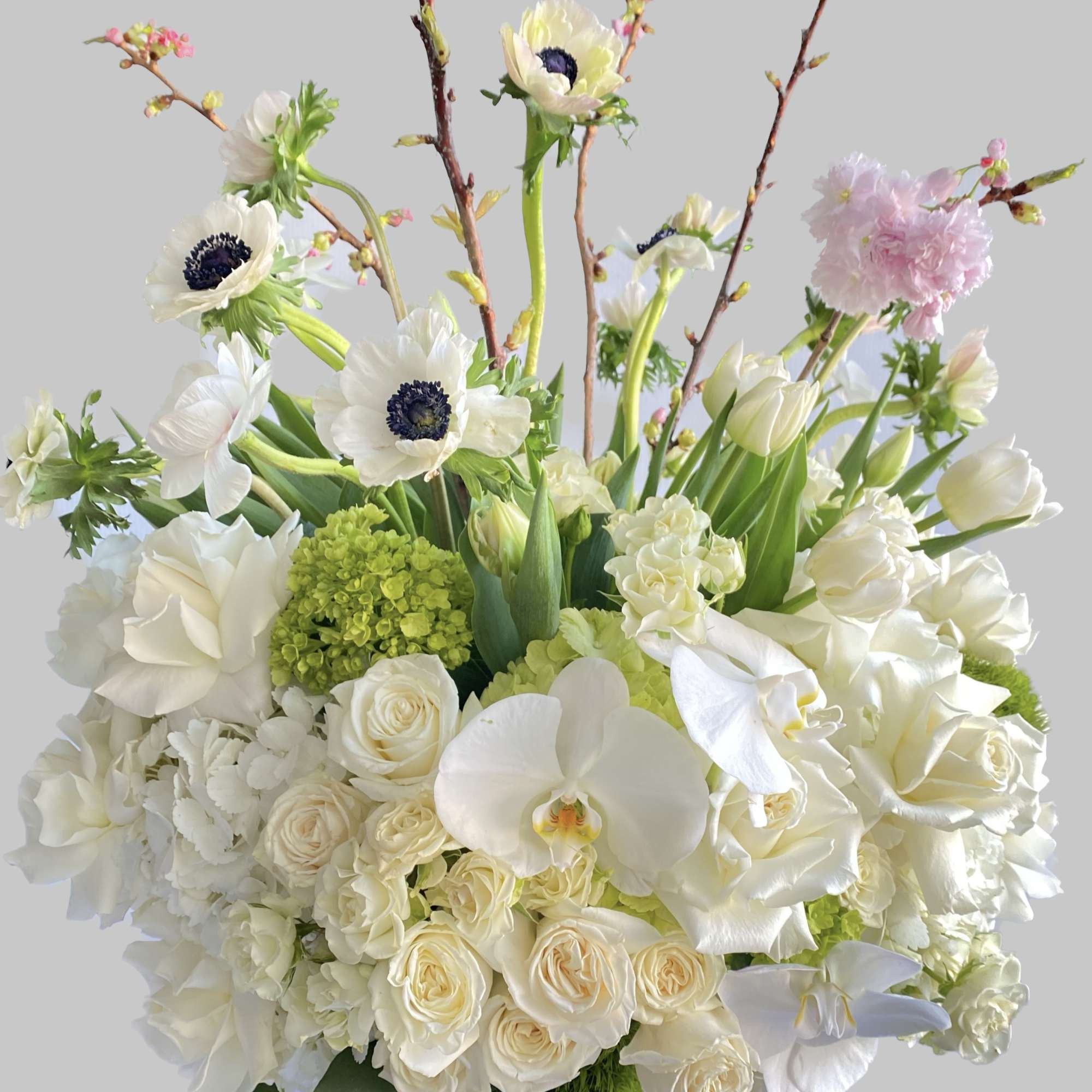 White floral arrangement with orchids, roses, and tulips in a vase