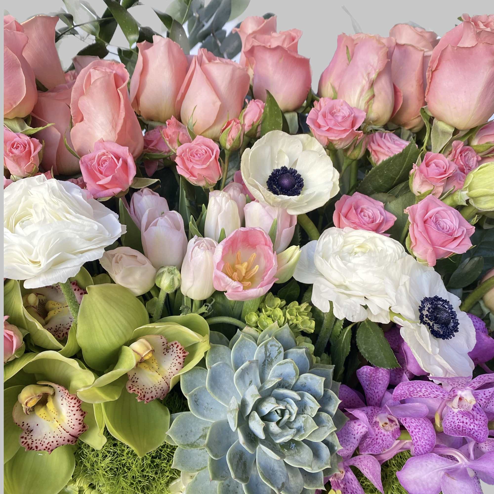 Mixed bouquet with pink roses, white anemones, orchids, and a blue succulent