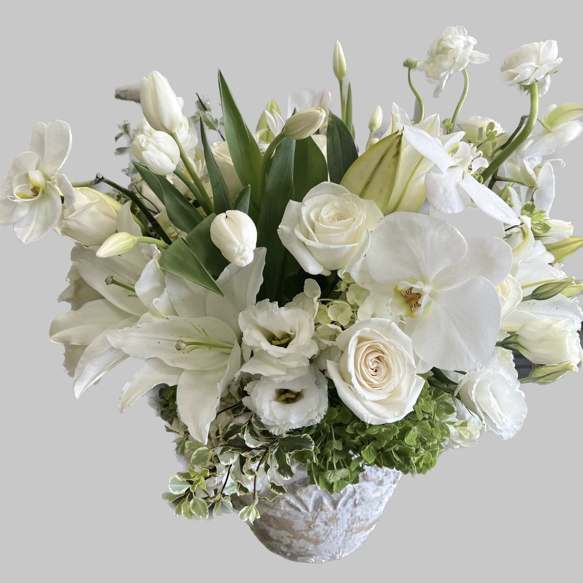 White floral arrangement in a textured vase with lilies and roses