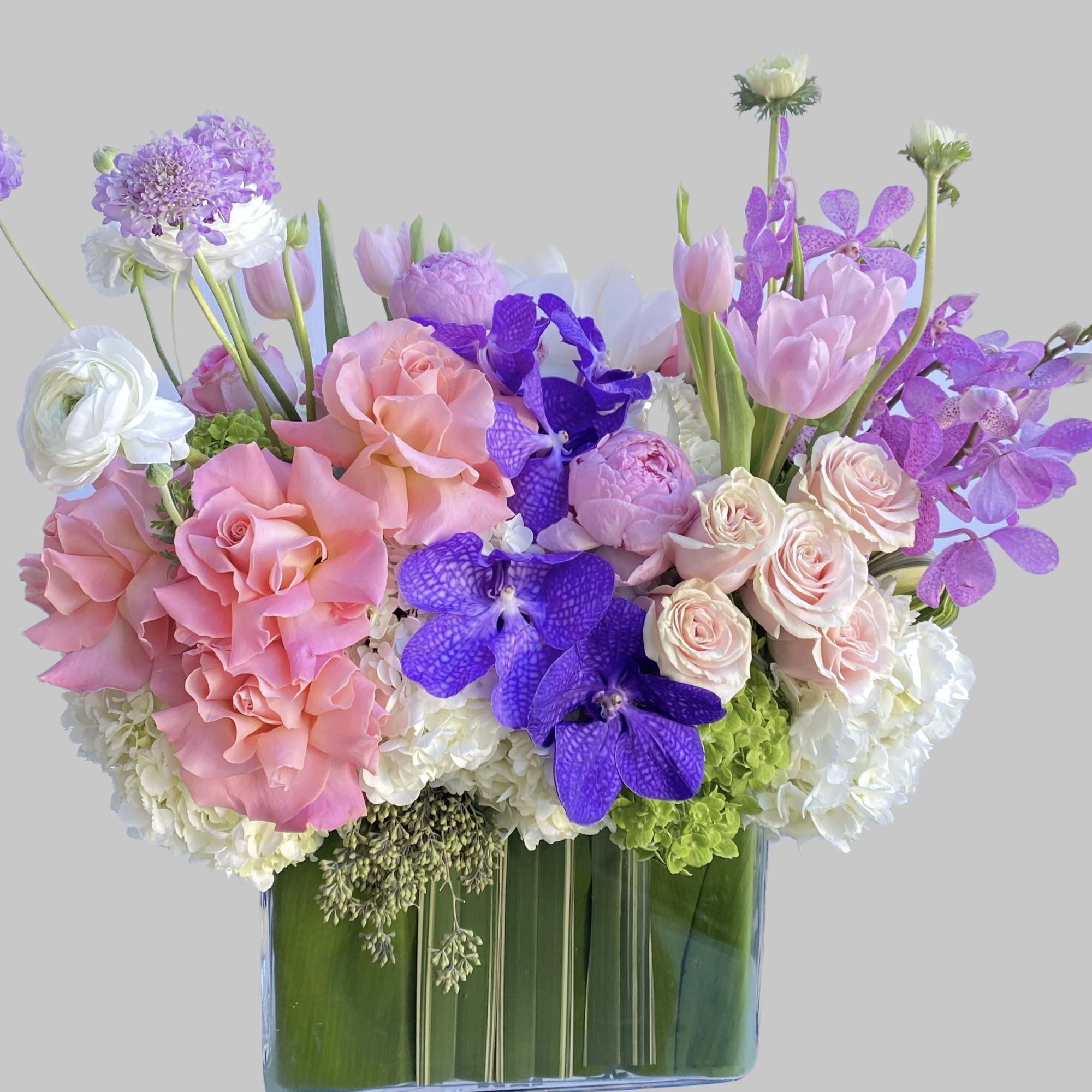 Pink, purple, and white flowers arranged in a clear glass vase