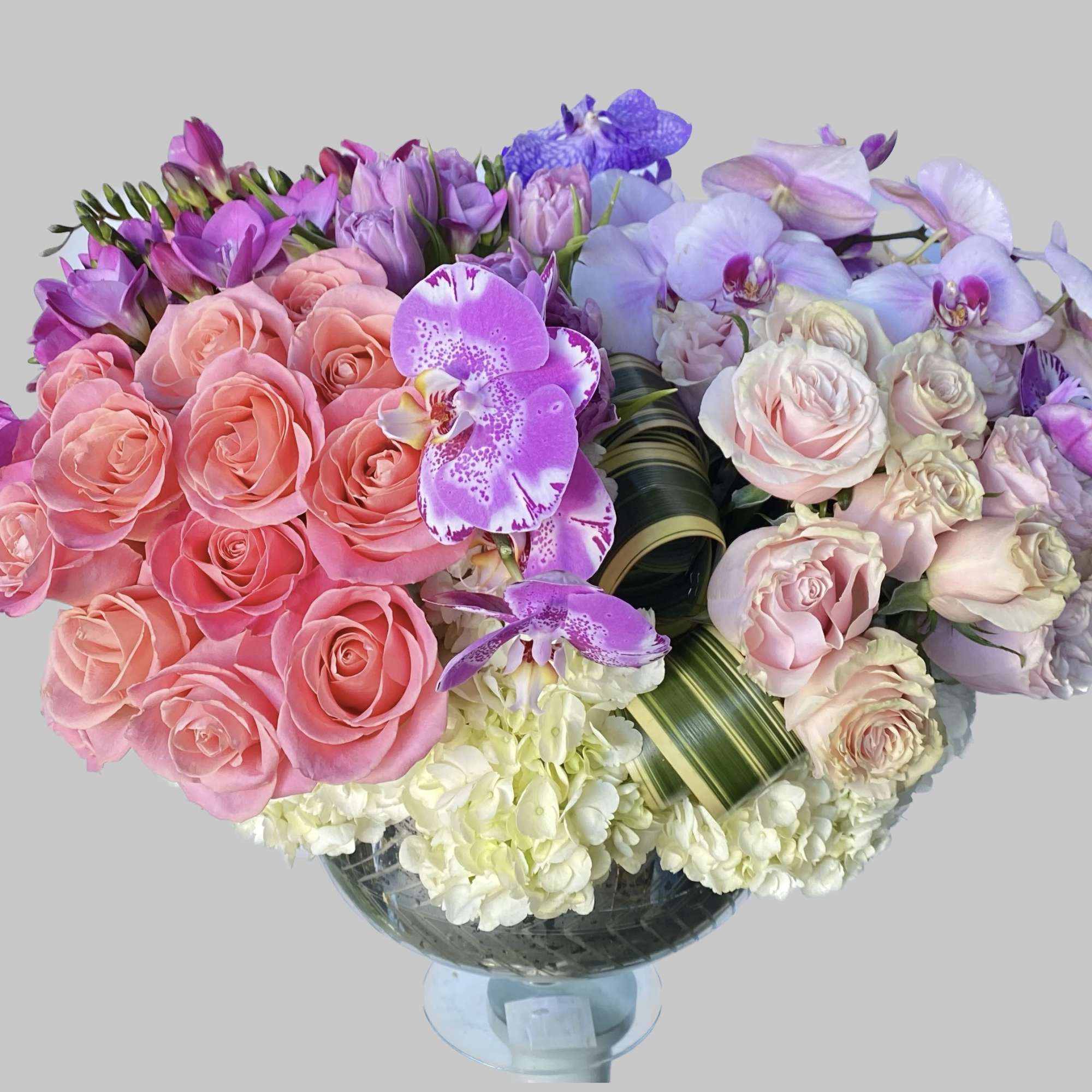 Bouquet of pink roses and purple orchids in a glass vase