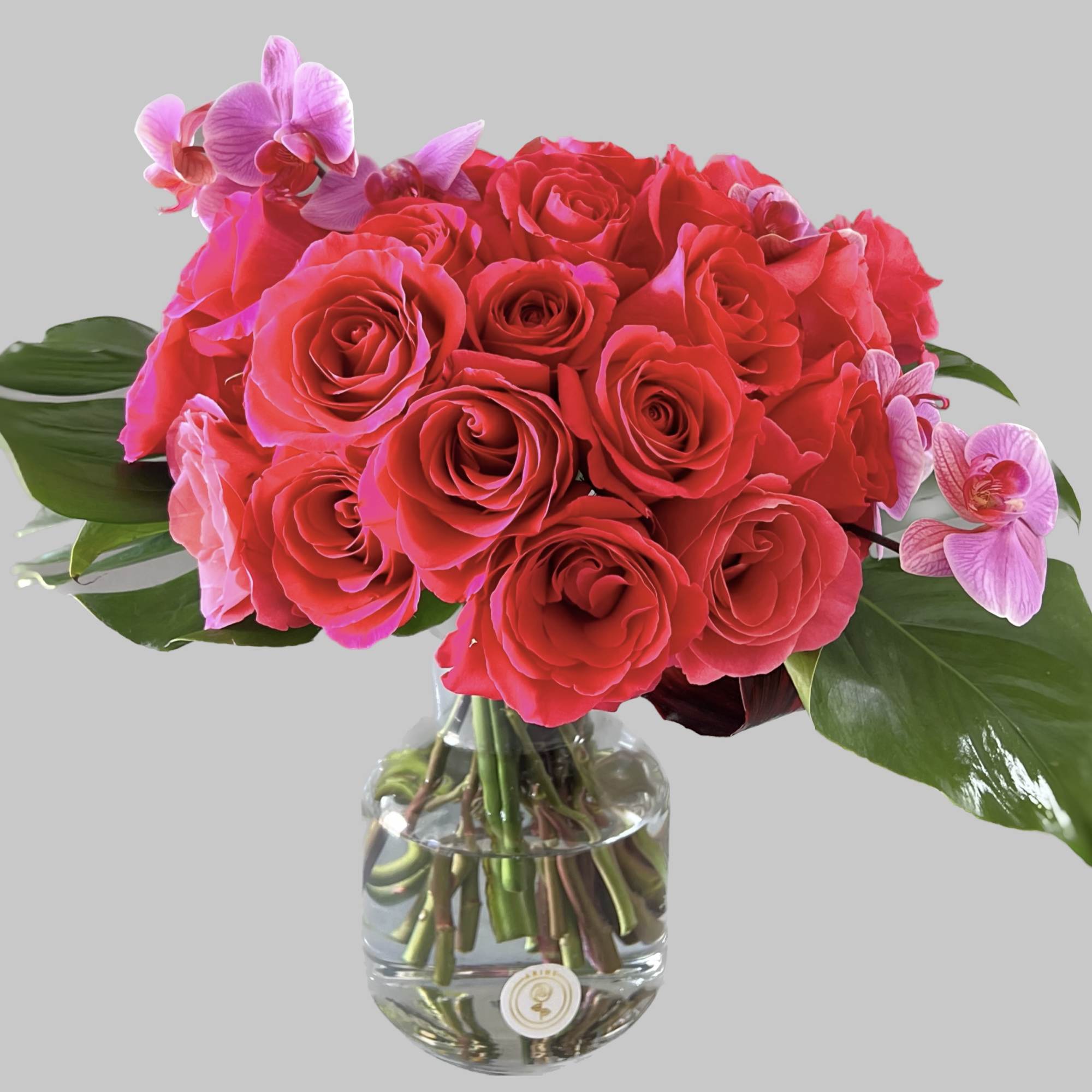 Pink roses with orchid accents in a clear glass vase