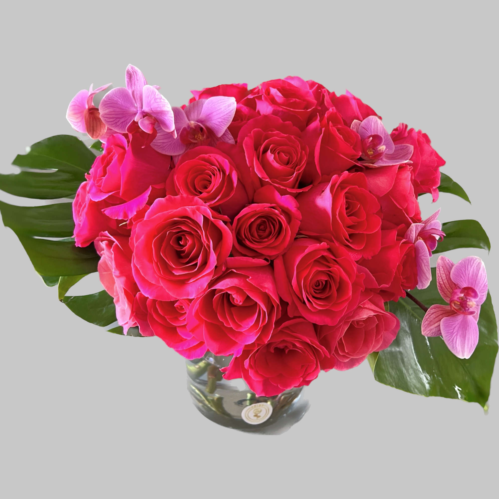 Hot pink roses arranged in a glass vase with pink orchids