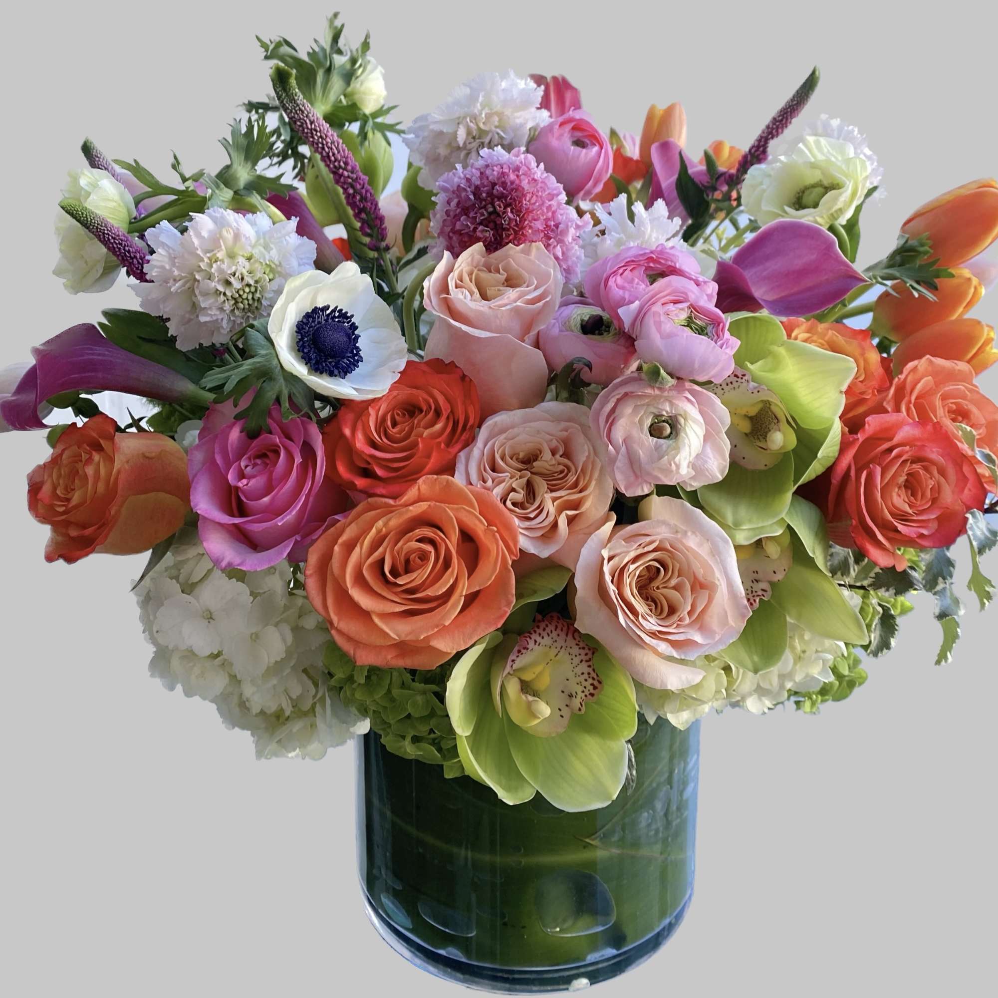 Mixed bouquet of roses, calla lilies, and orchids in a glass vase