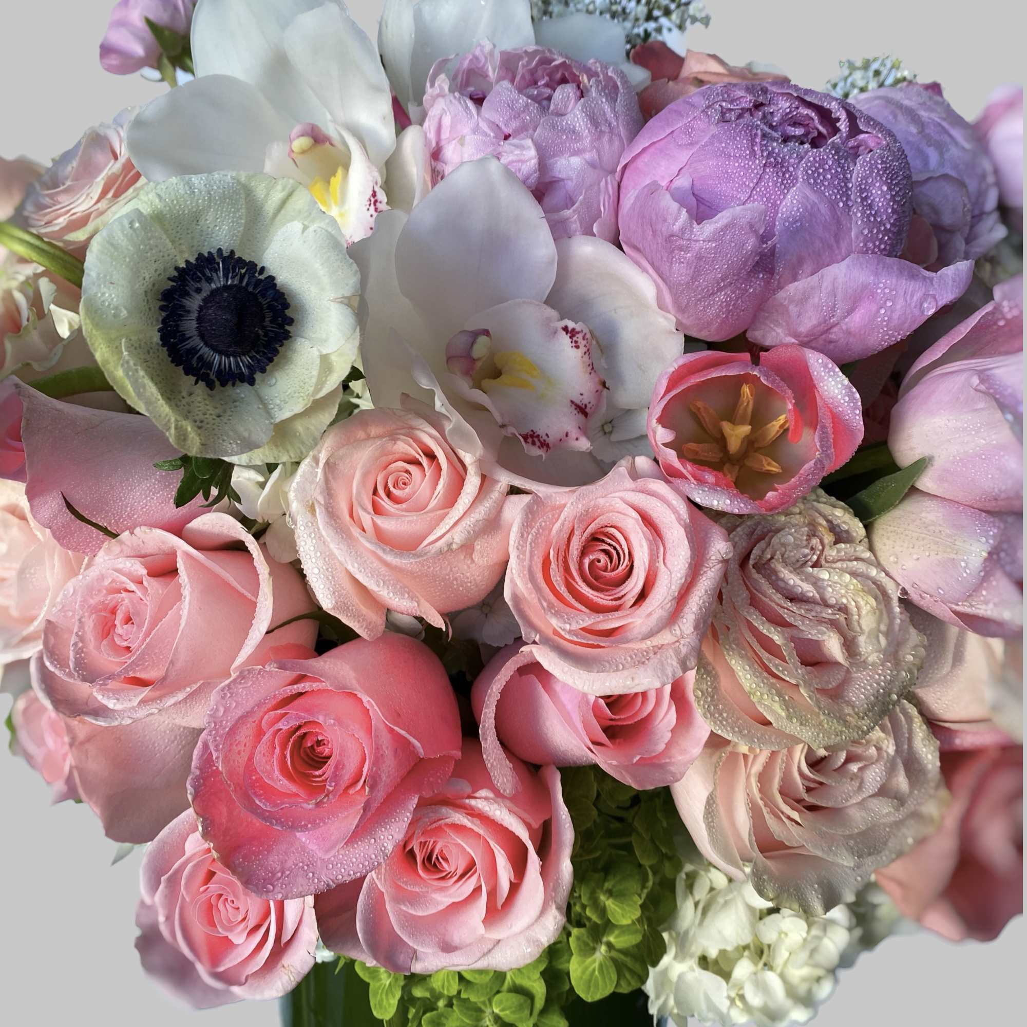 Pink and white bouquet with roses, tulips, and orchids in a vase