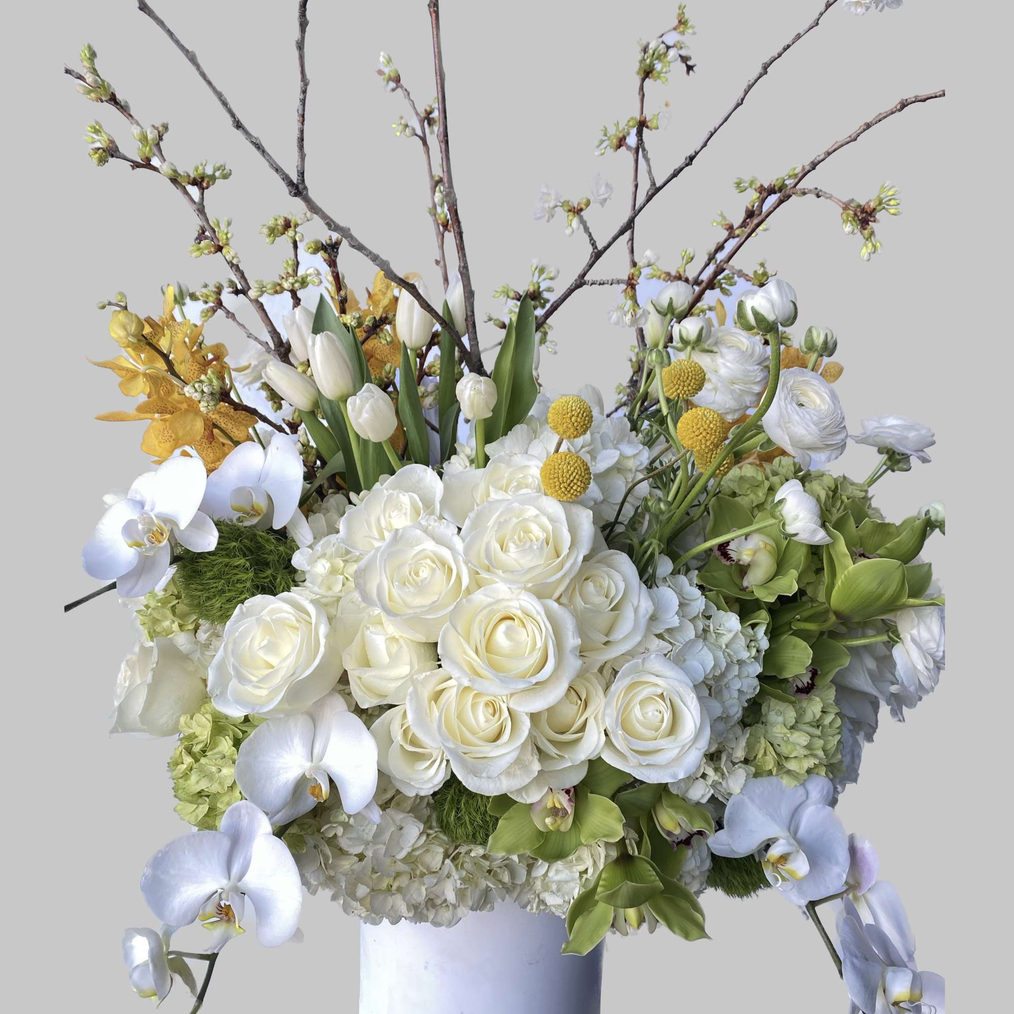 White roses, orchids, and tulips in a white vase