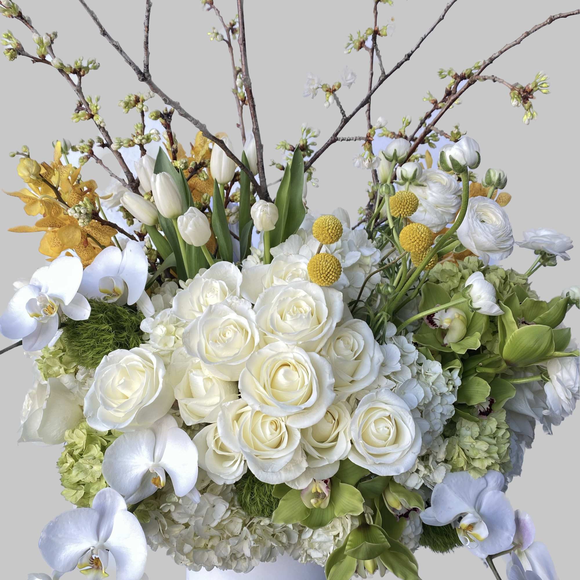 White and yellow floral arrangement in a white vase with tall branches