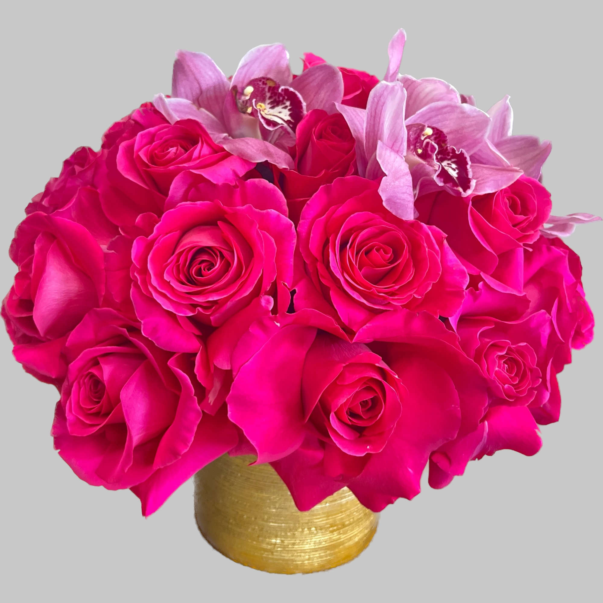 Hot pink roses and pale pink orchids in a gold vase