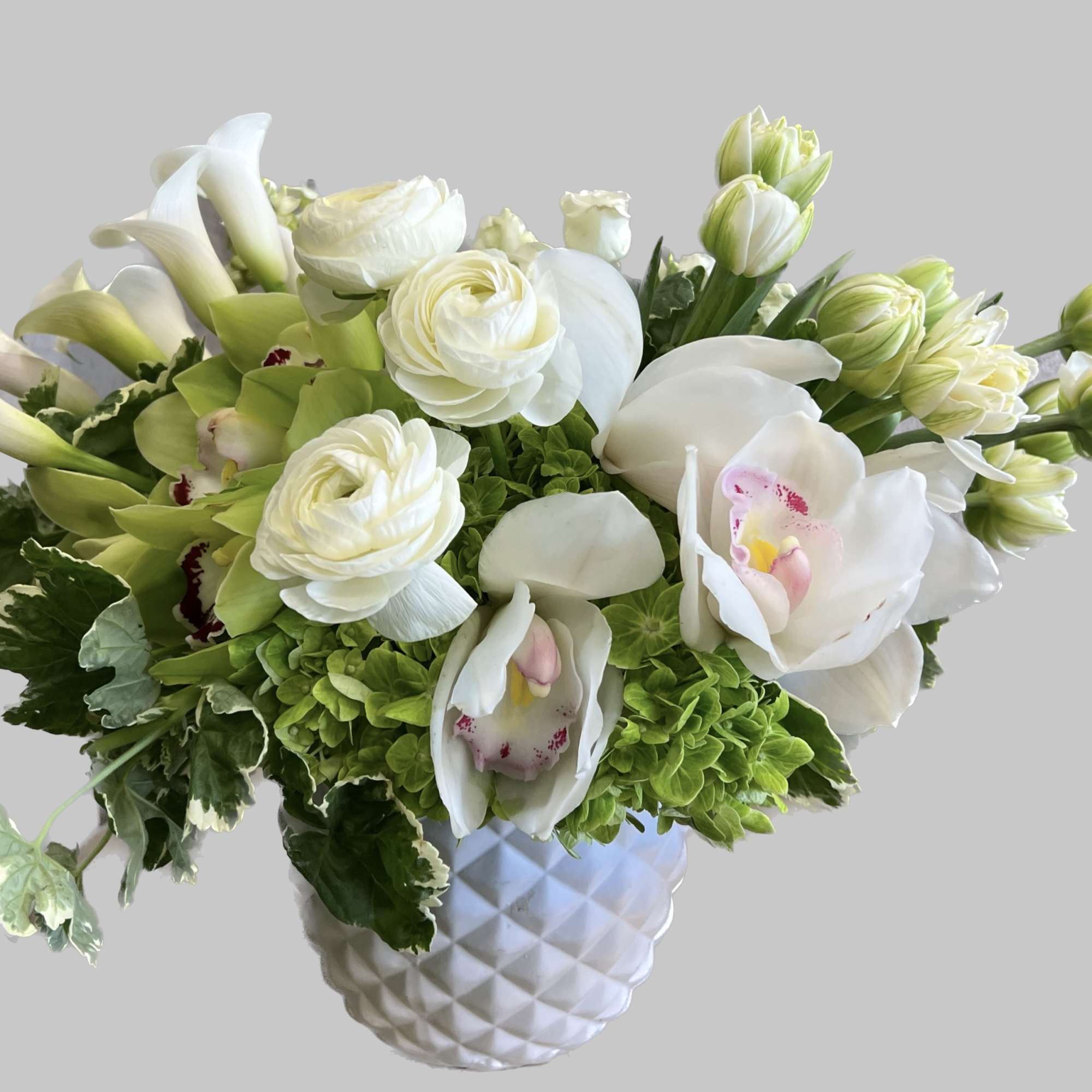 White and green floral arrangement in a textured white vase