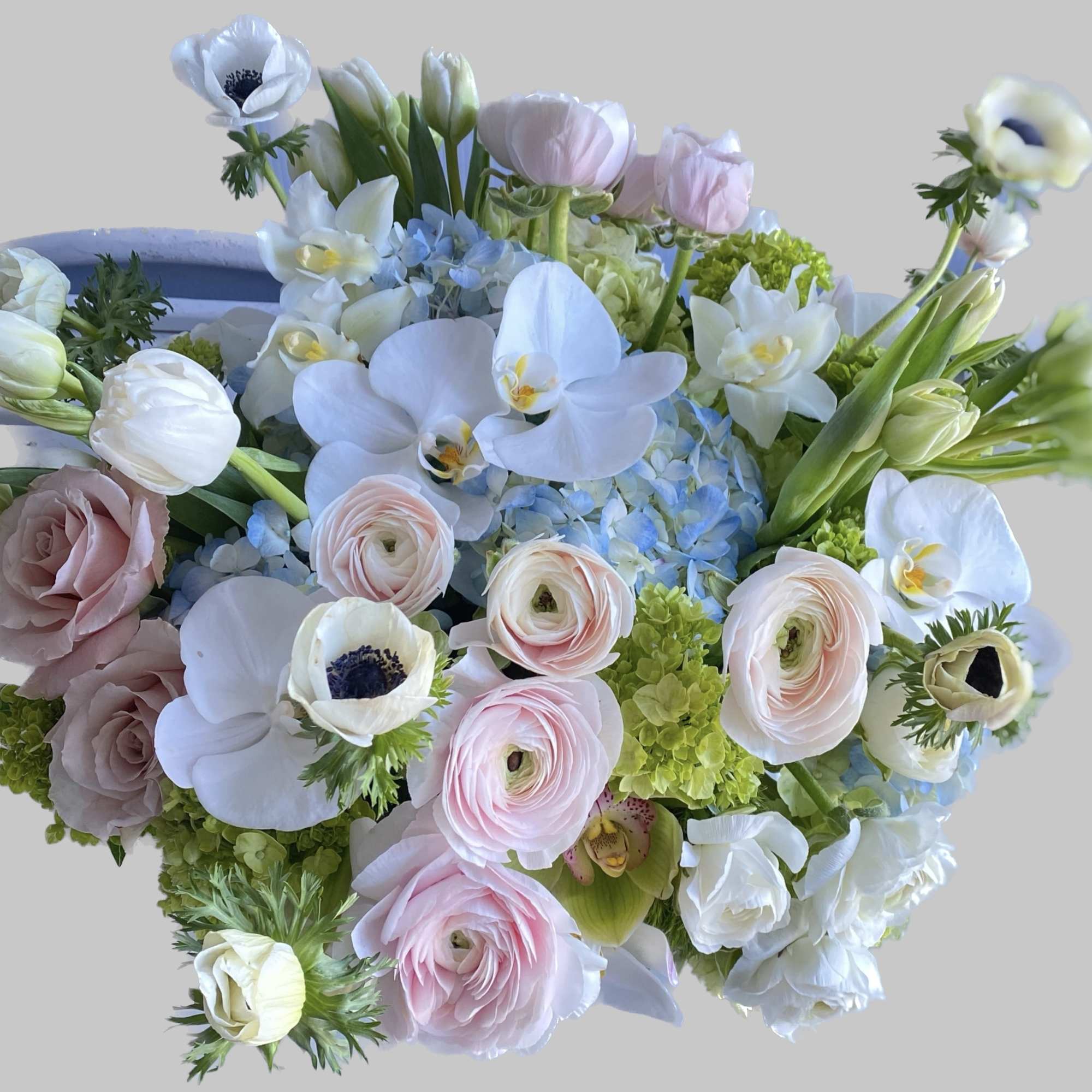 Pastel bouquet with white orchids, pink ranunculus, and pale roses