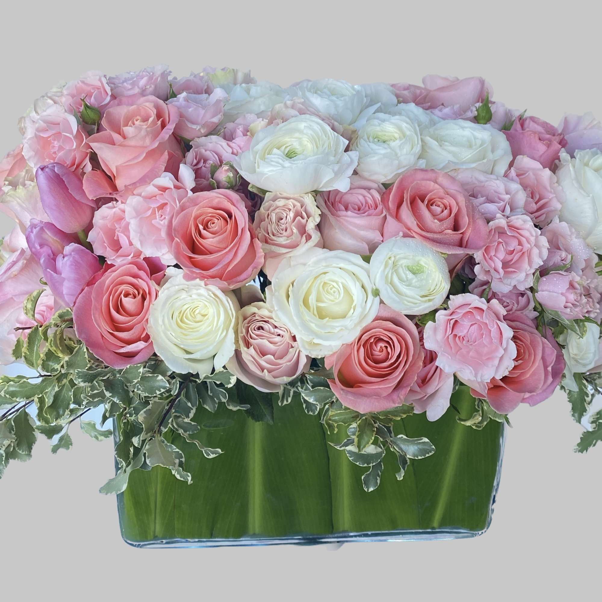 Pink and white roses arranged in a low glass vase