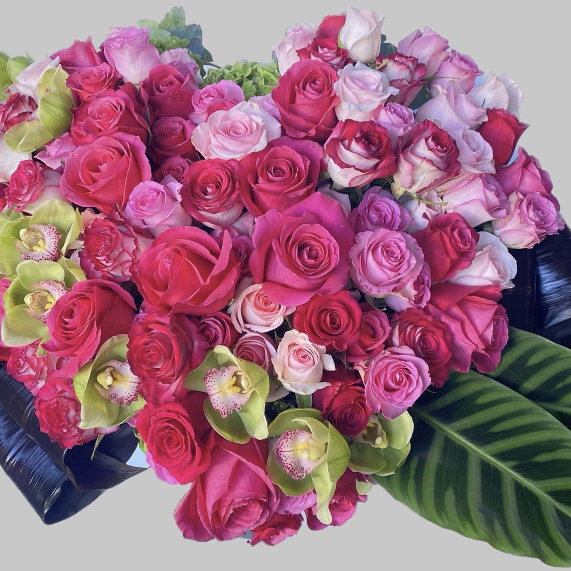 Heart-shaped bouquet of pink roses with green orchids and dark leaves
