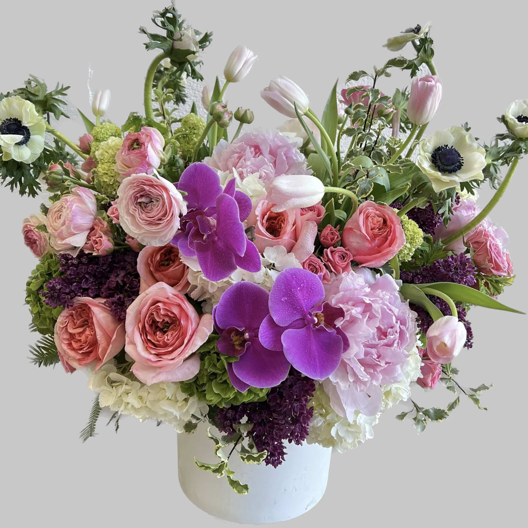 Pink and white floral arrangement with orchids and roses in a white vase