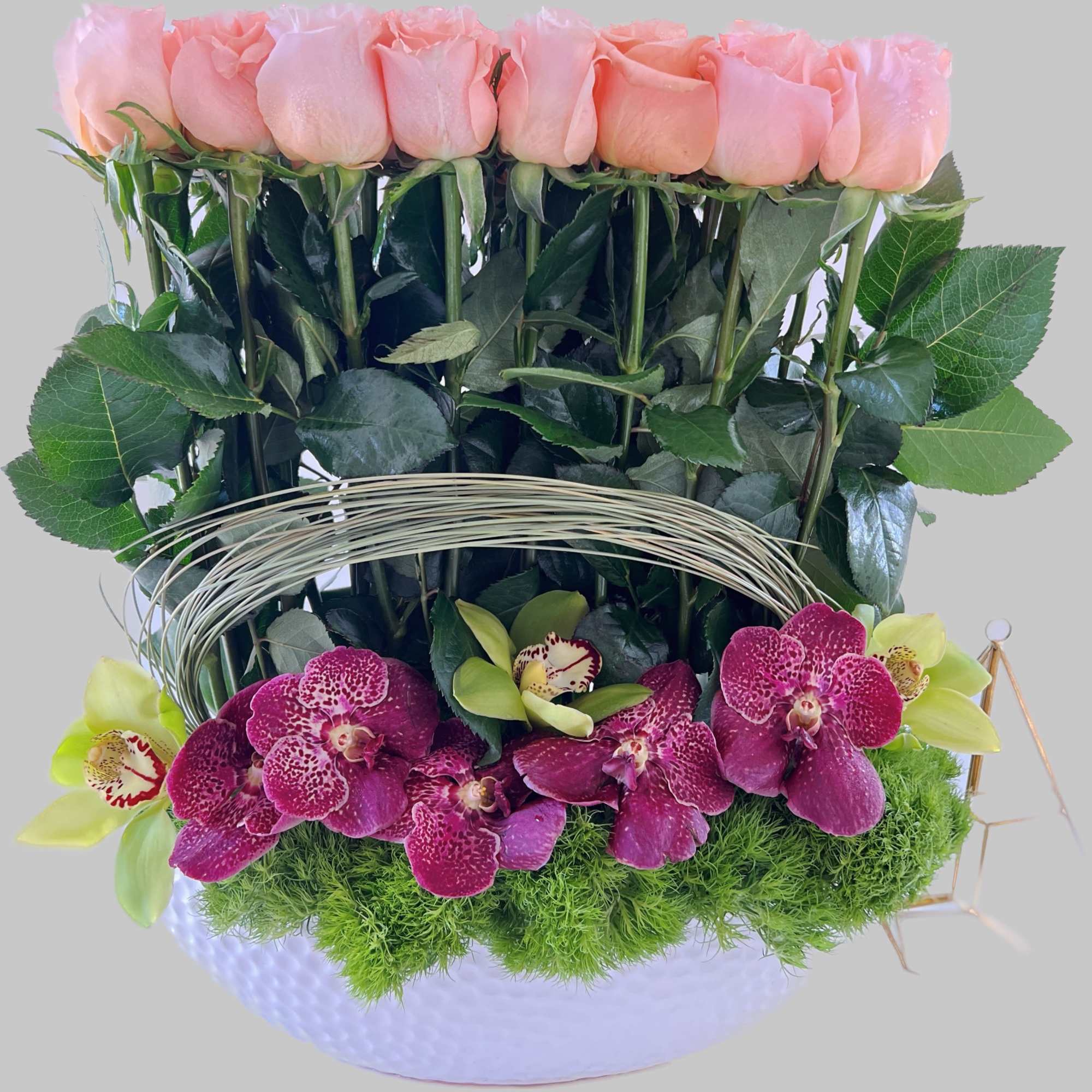 Pink roses and magenta orchids arranged in a white vase