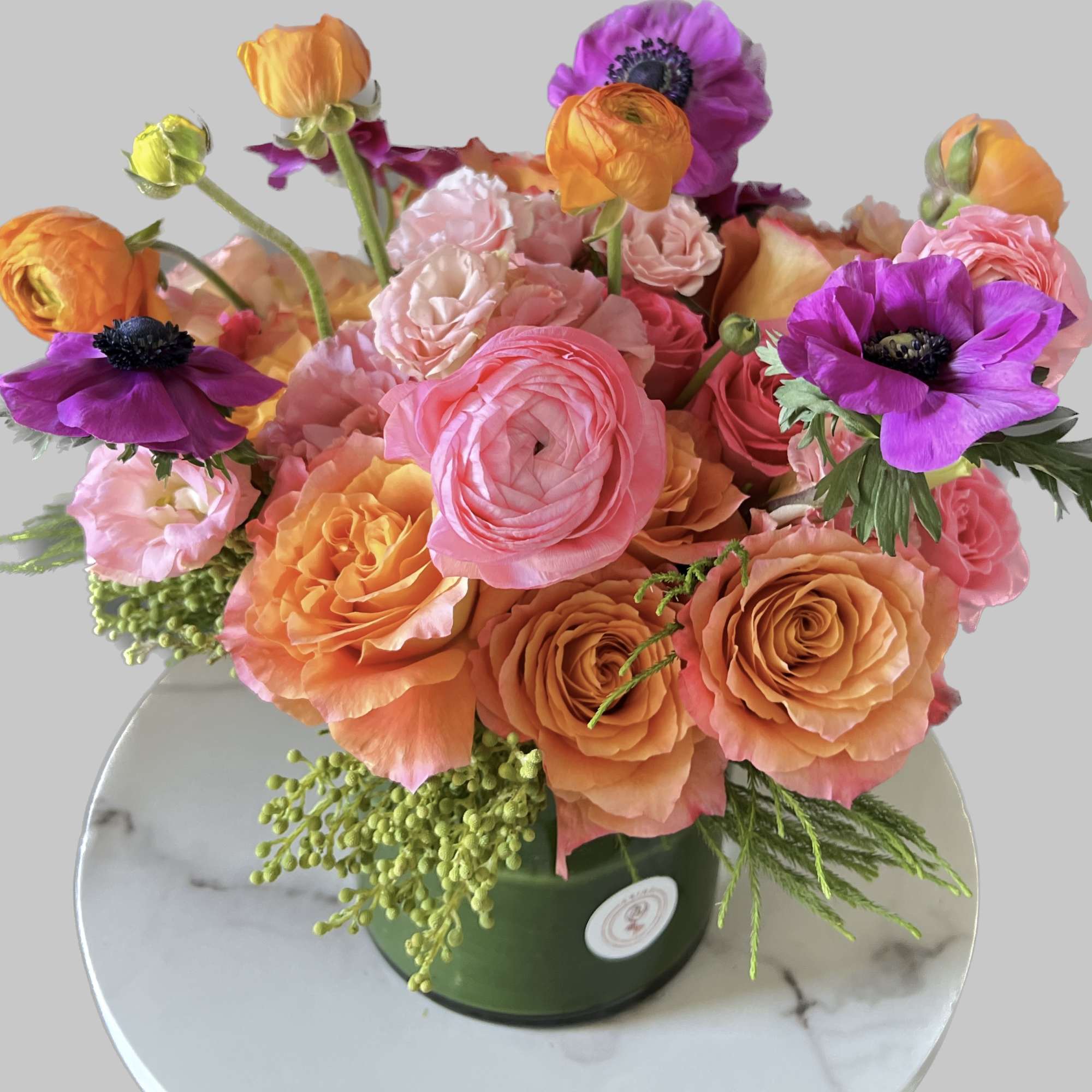 Bouquet of pink, orange, and purple flowers in a green vase