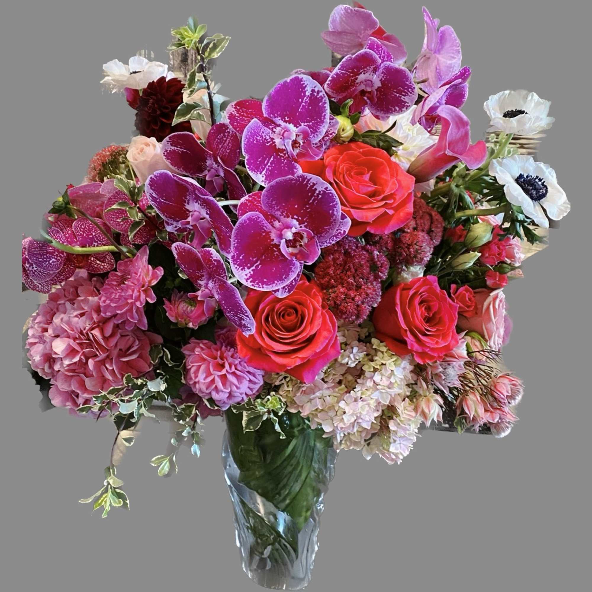 Mixed bouquet of pink orchids, roses, and hydrangeas in a glass vase