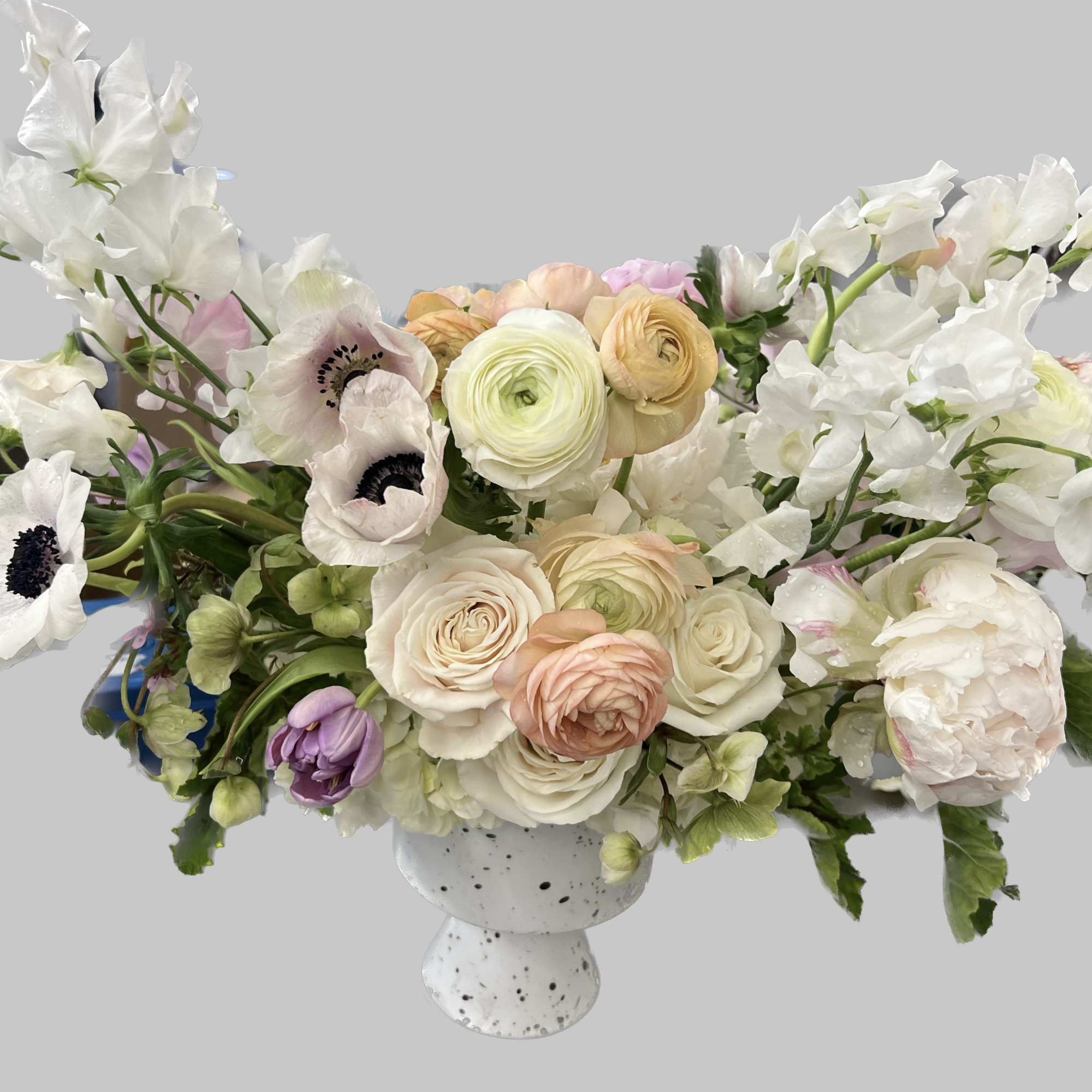 White and blush floral arrangement in a speckled pedestal vase