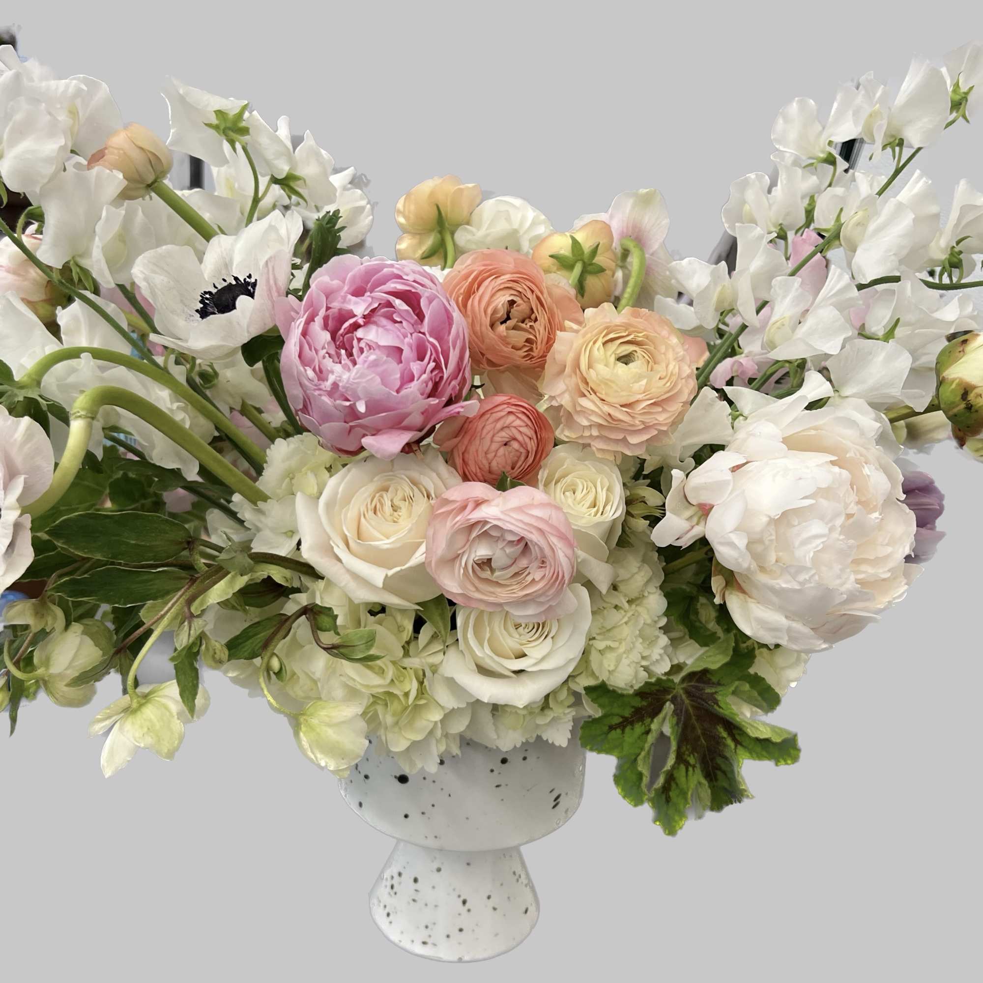 Pastel bouquet of white, pink, and peach flowers in a speckled white vase